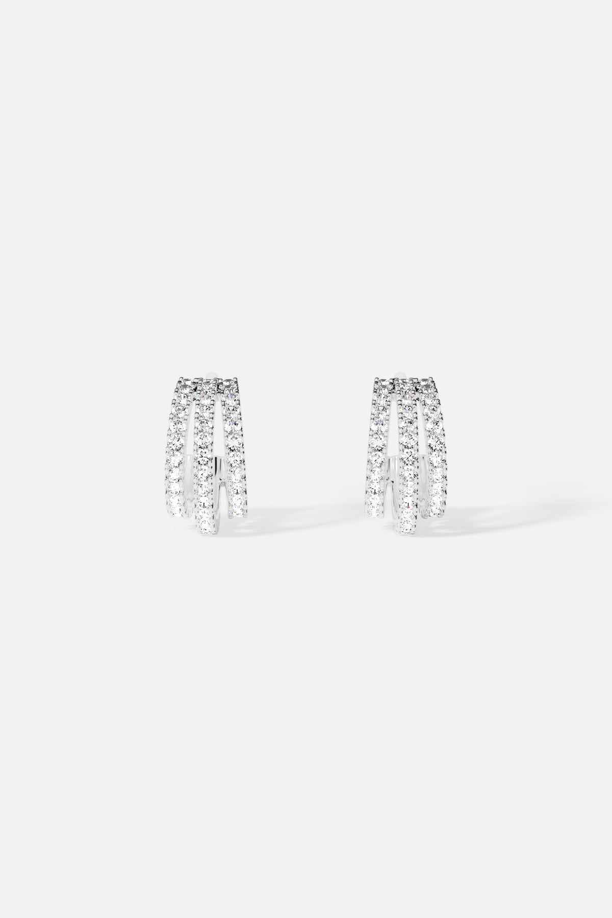 Boucles d'oreilles APM, trois arches scintillantes en finition rhodium, éclat contemporain.