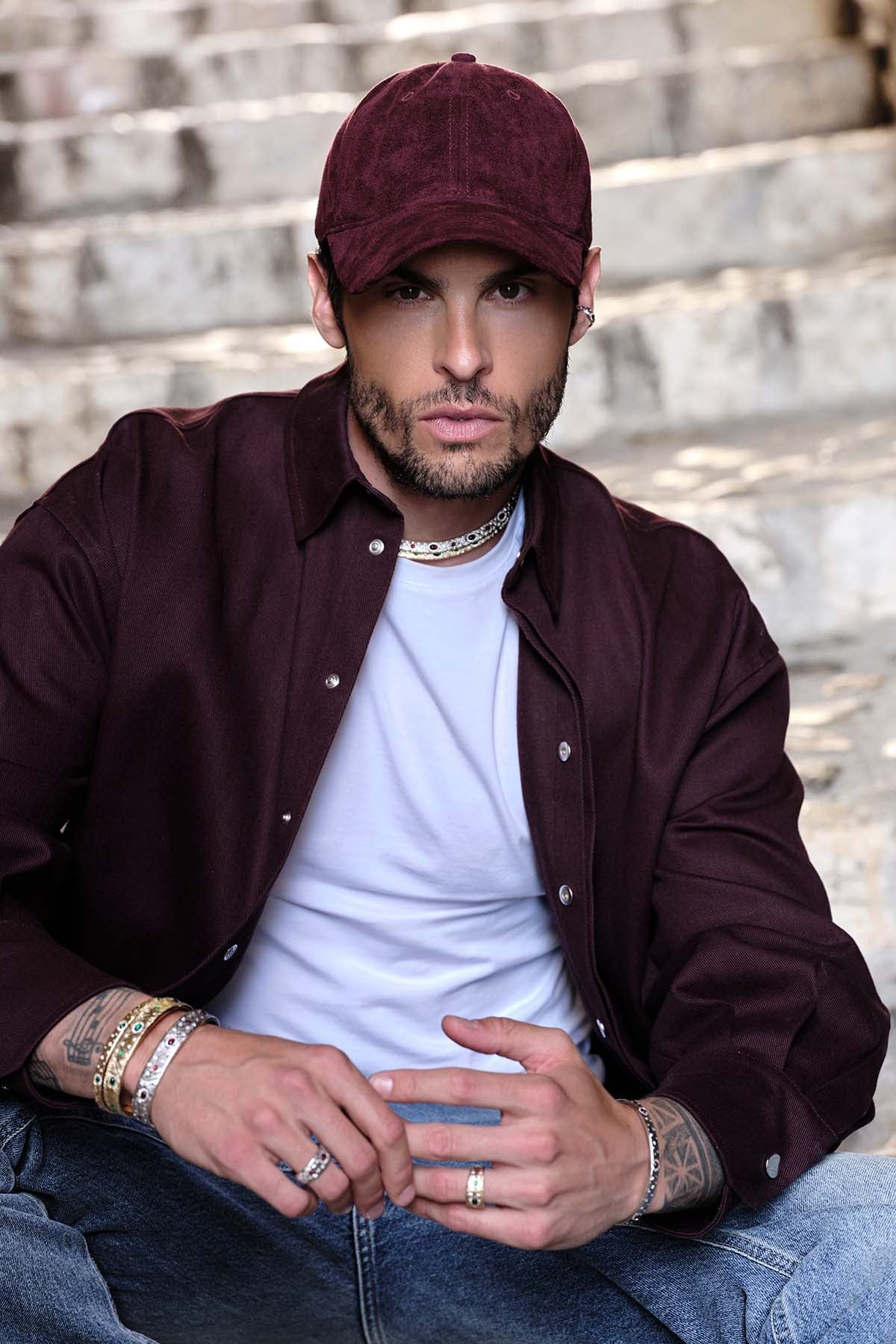 Man wearing APM bracelets and rings, allure urbaine et raffinée sous le soleil.