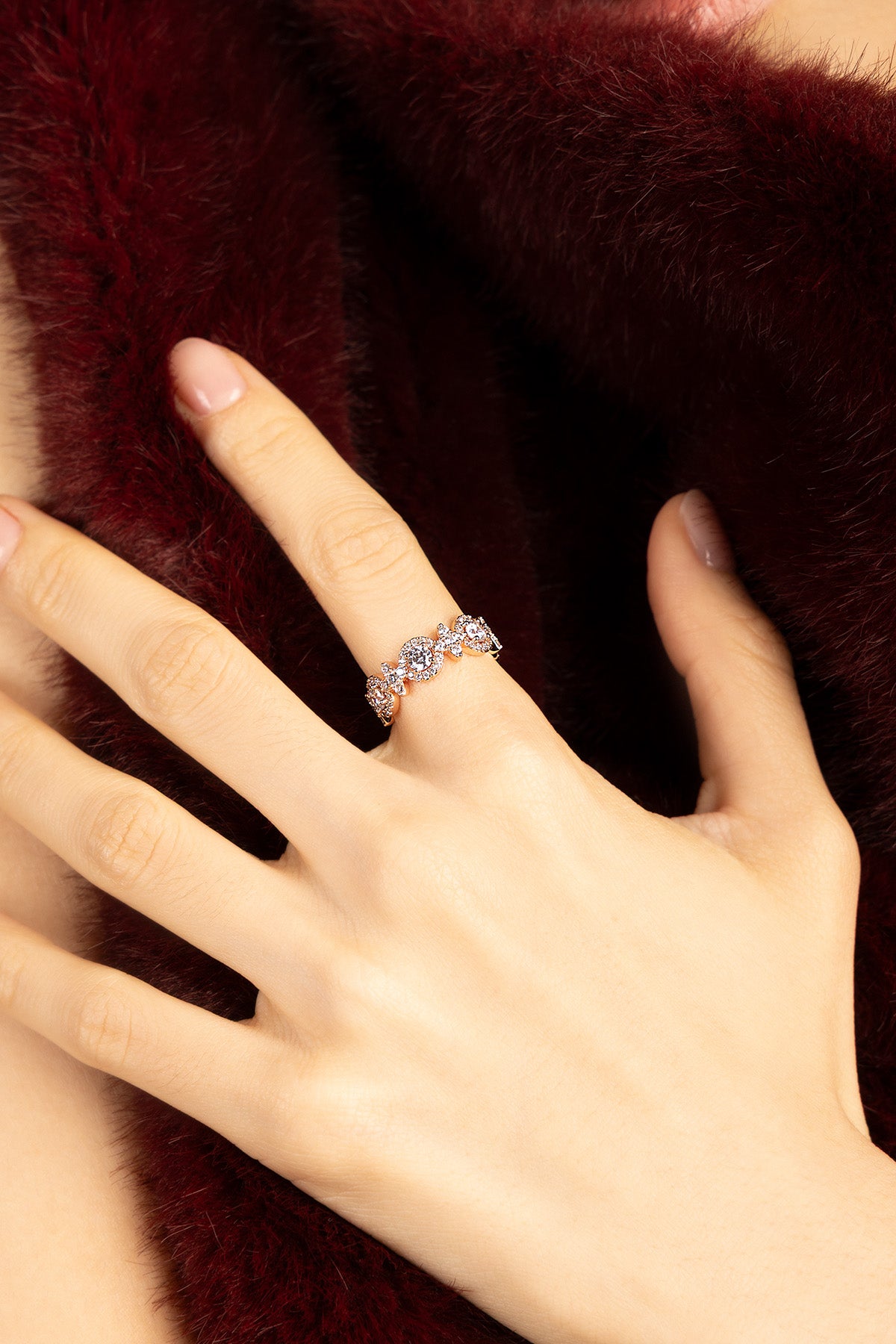 Femme portant la bague APM Monaco, éclat délicat sur velours bordeaux.