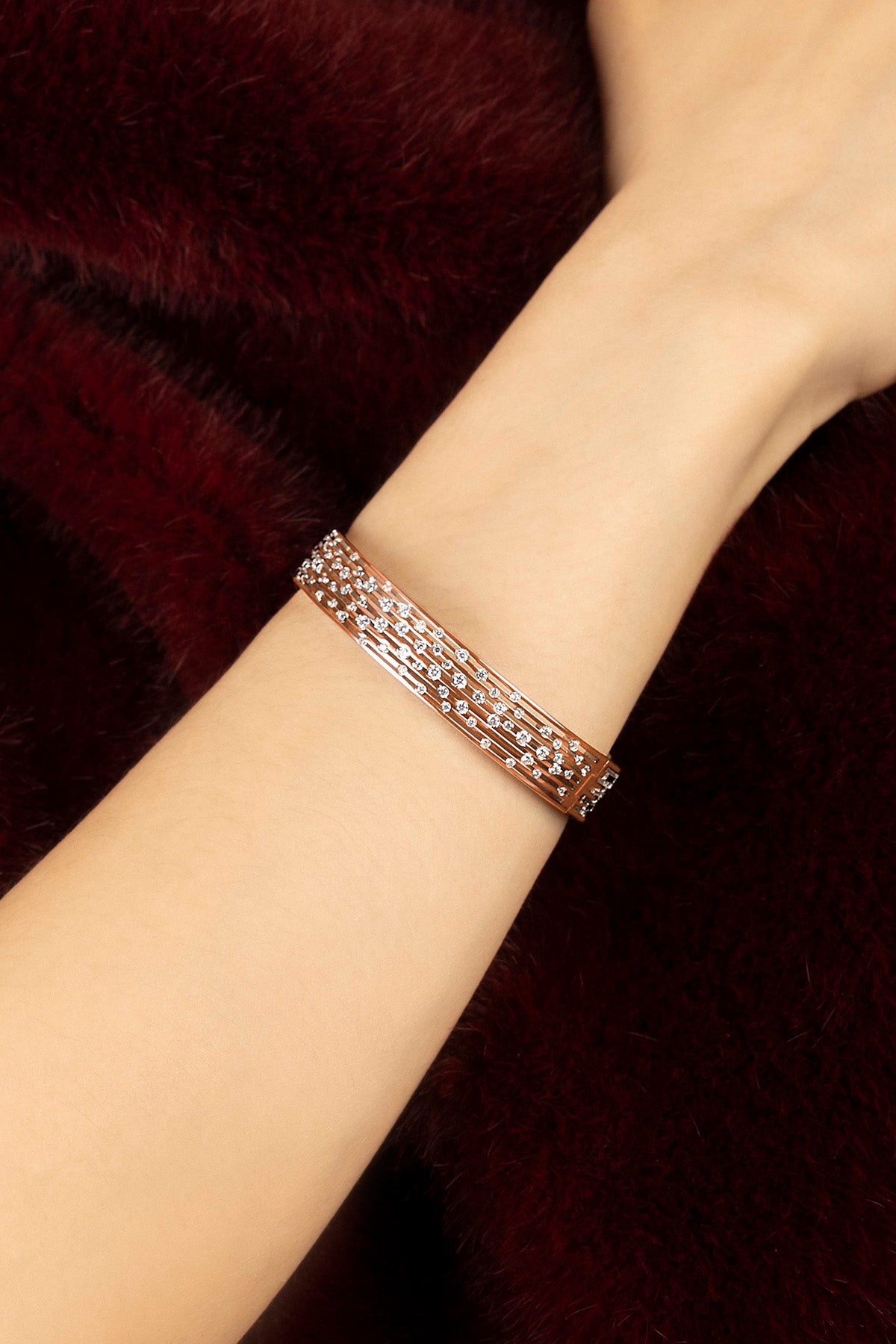 Femme portant le bracelet APM Monaco, éclat scintillant sur velours bordeaux.