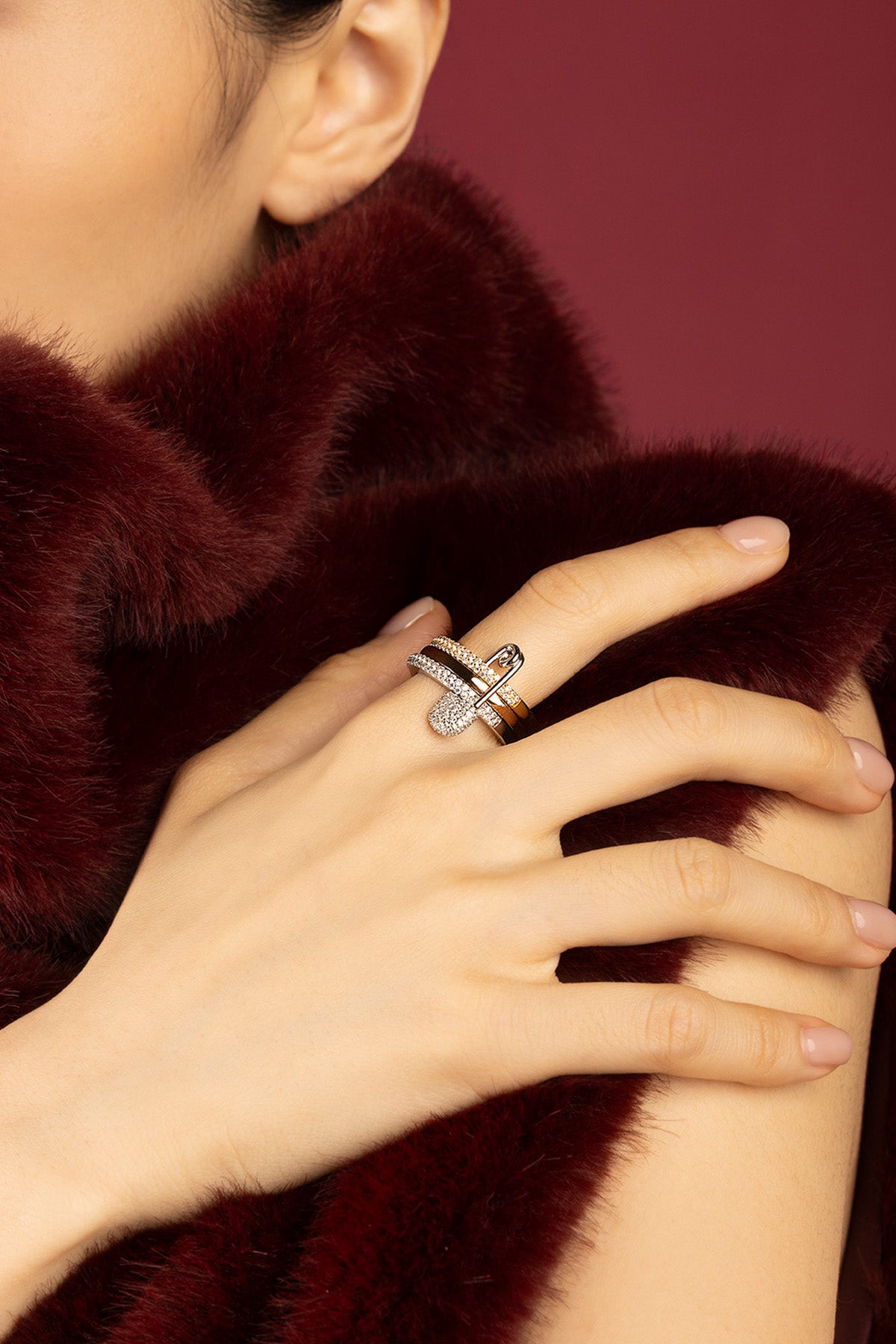 Woman wearing APM bague, éclat scintillant sur fourrure bordeaux, élégance intemporelle.