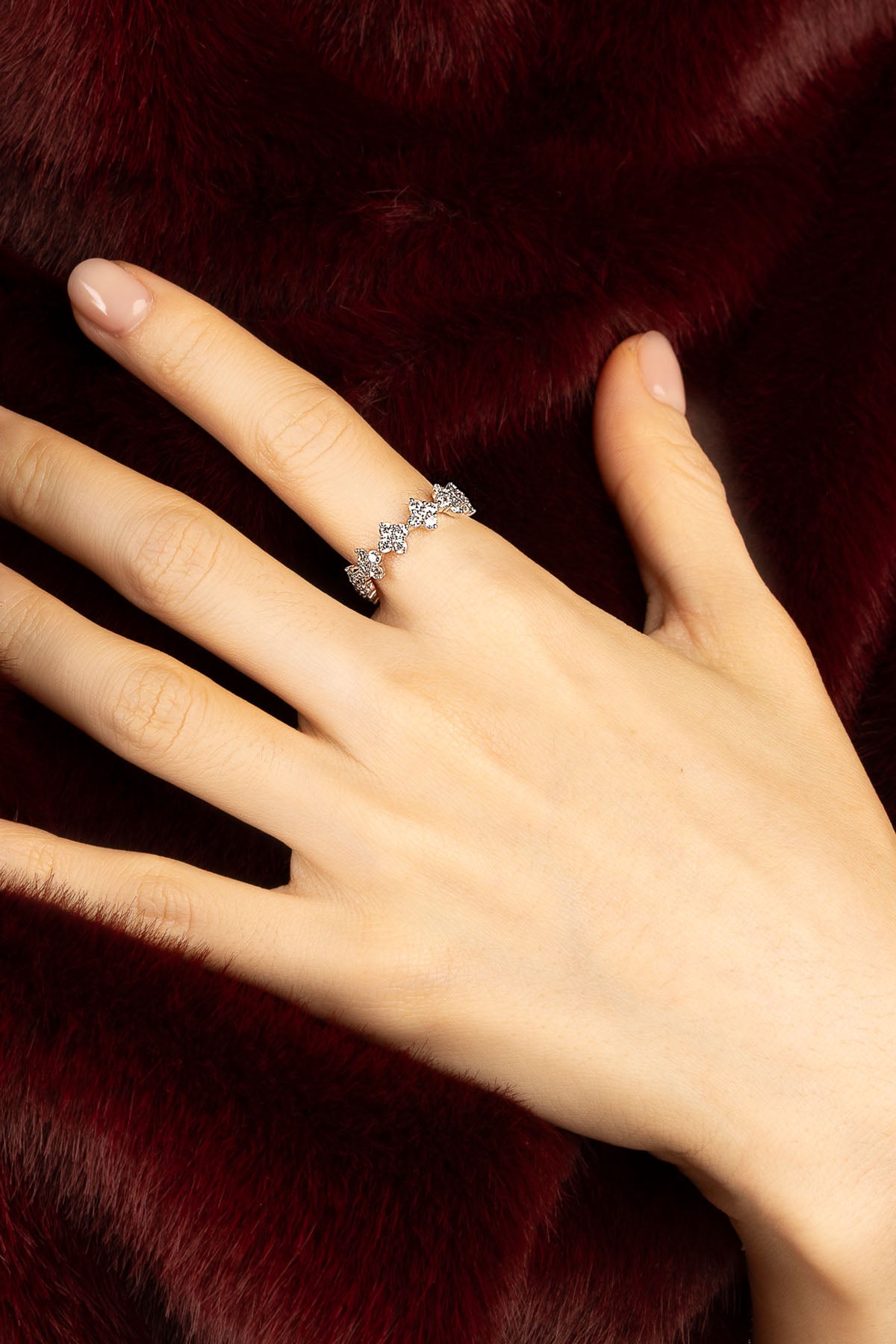 Femme portant la bague APM Monaco, éclat scintillant sur fourrure bordeaux.