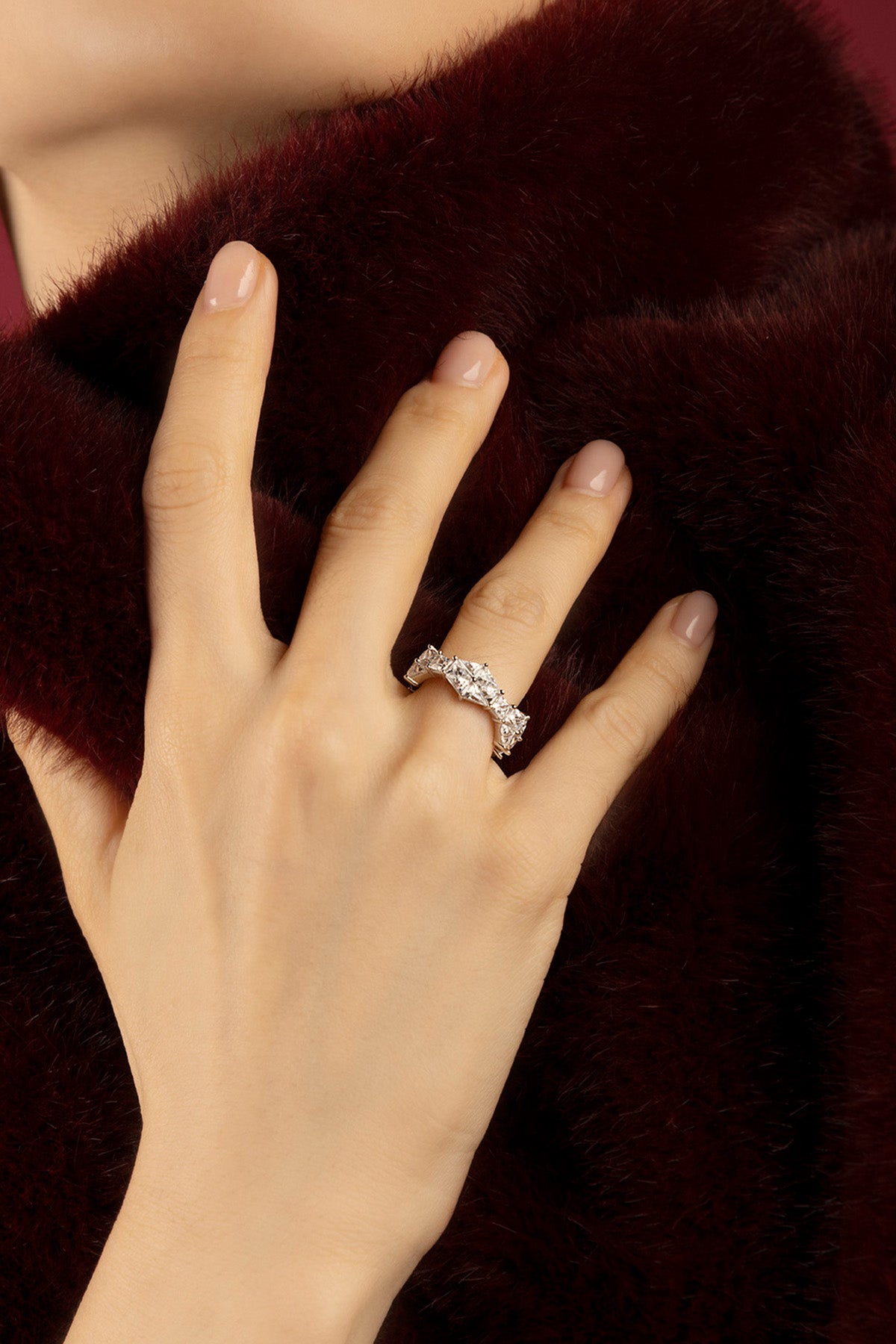 Femme portant la bague APM Monaco, éclat scintillant sur velours bordeaux.