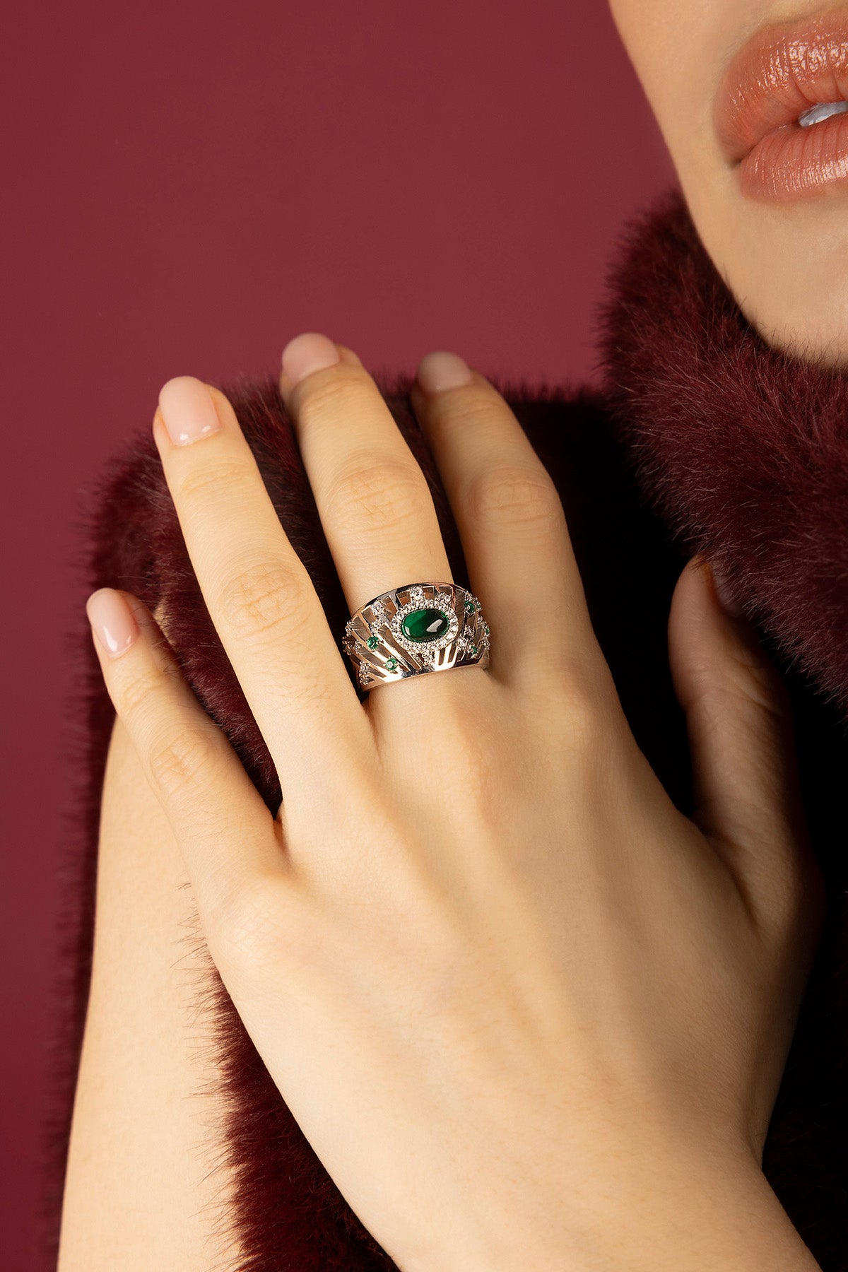 Femme portant la bague APM Monaco, éclat vert émeraude et allure royale.