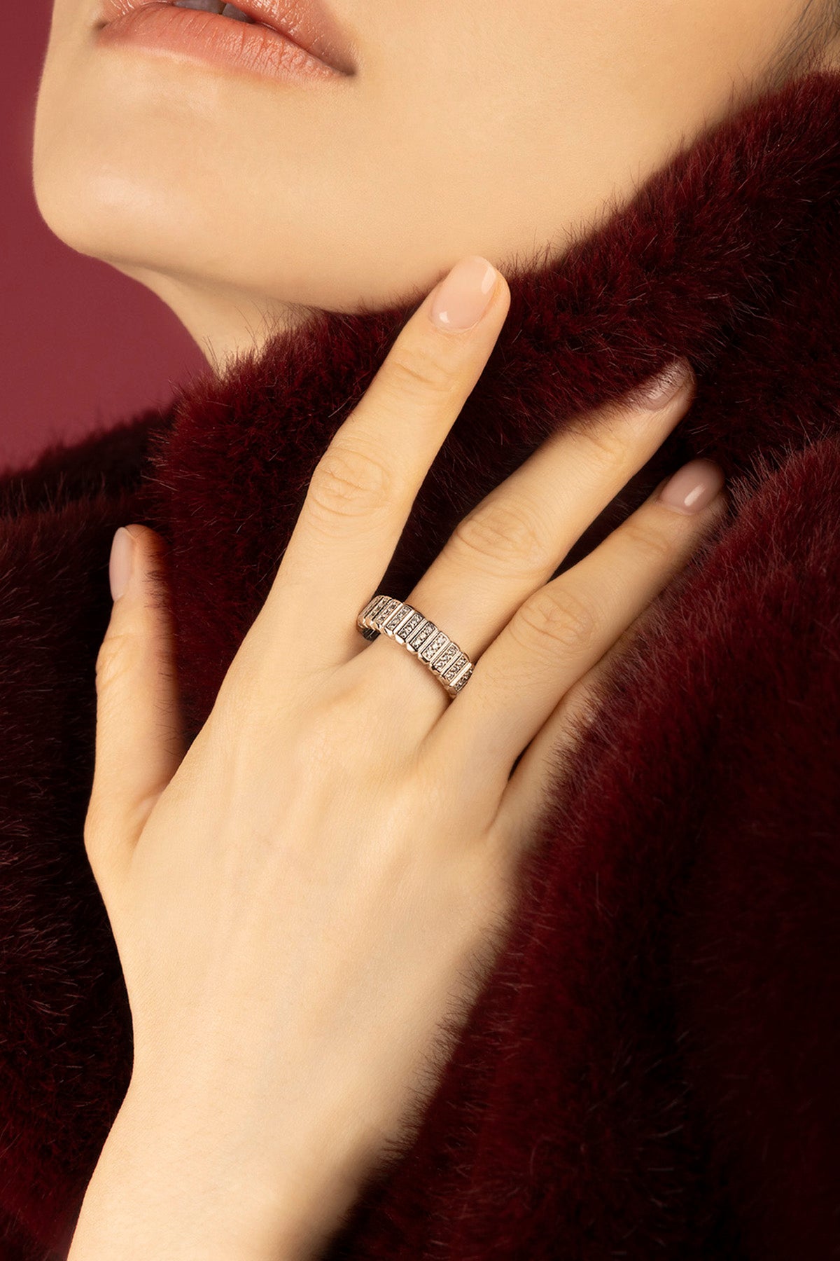 Femme portant la Bague Morse APM, éclat feutré sur fourrure bordeaux.