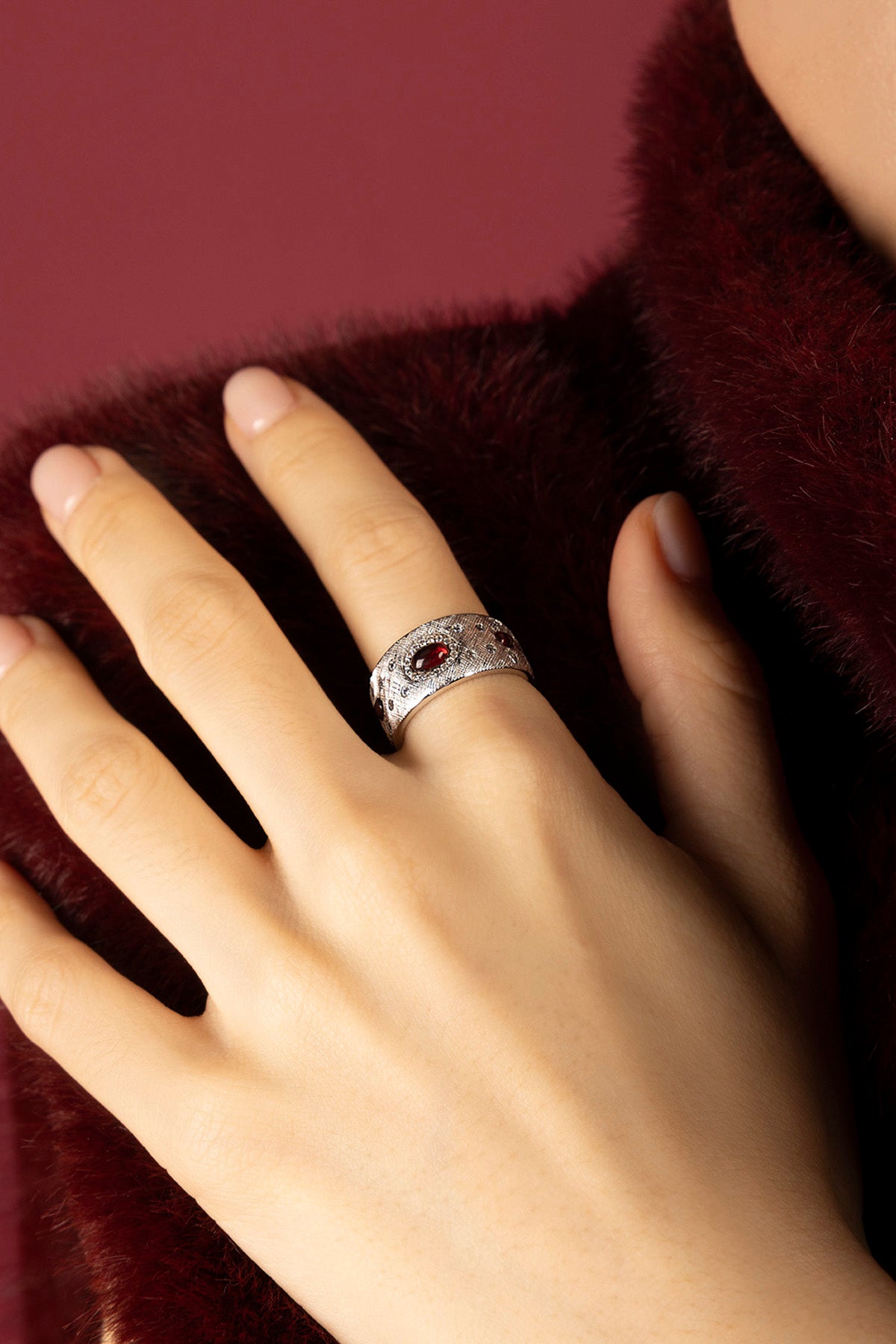 Femme portant la Bague APM Monaco, une élégance feutrée aux reflets rouges intenses.