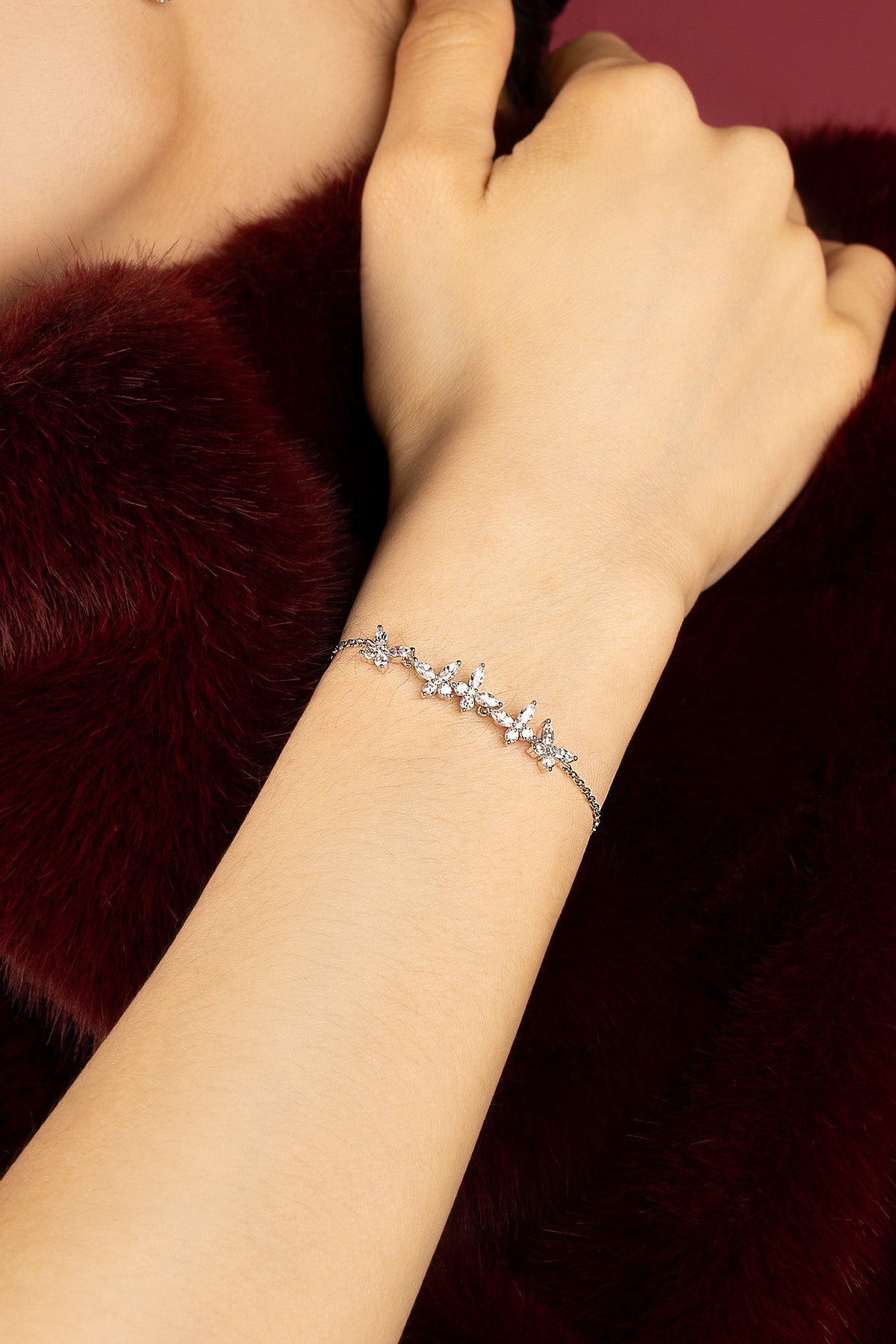 Femme portant le bracelet APM, envolée de papillons scintillants au poignet.