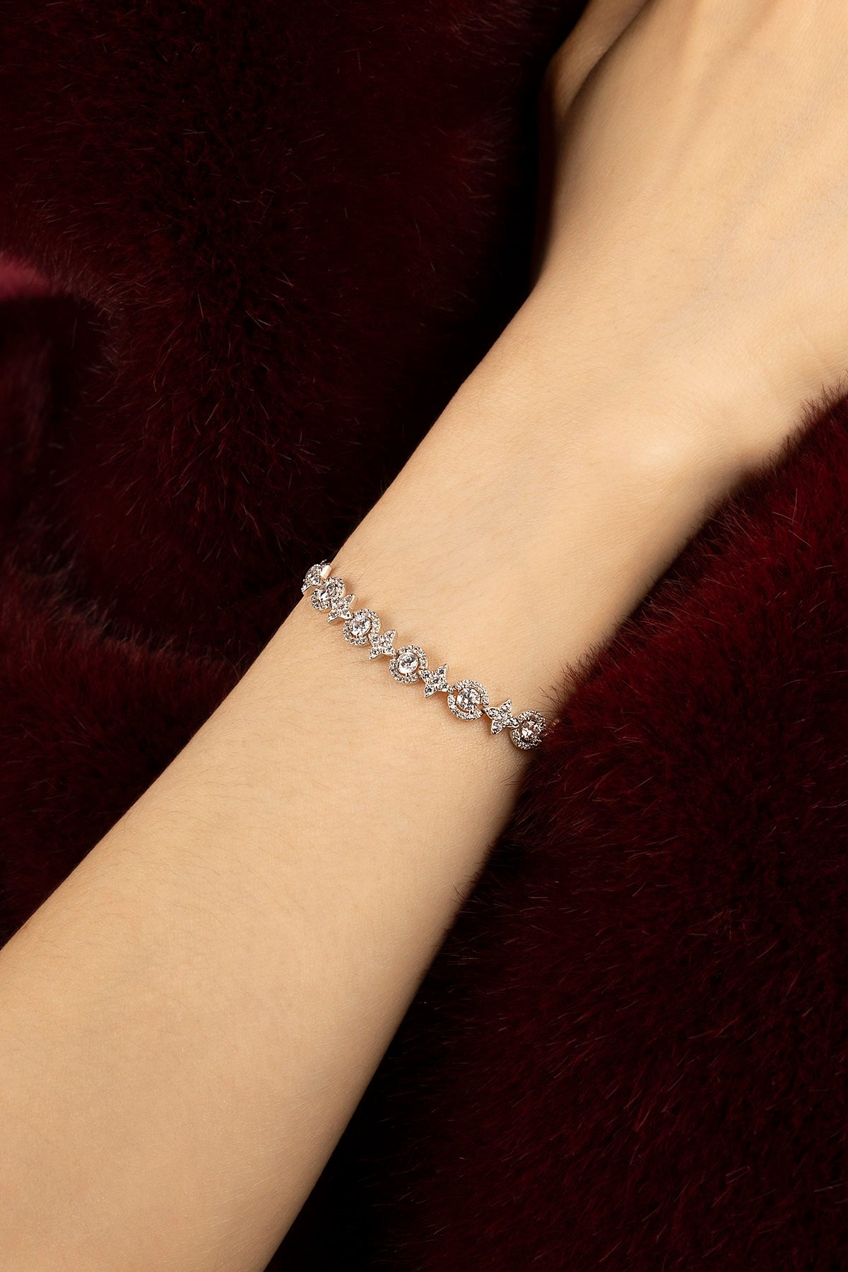 Femme portant un bracelet APM, éclat délicat sur fourrure bordeaux.