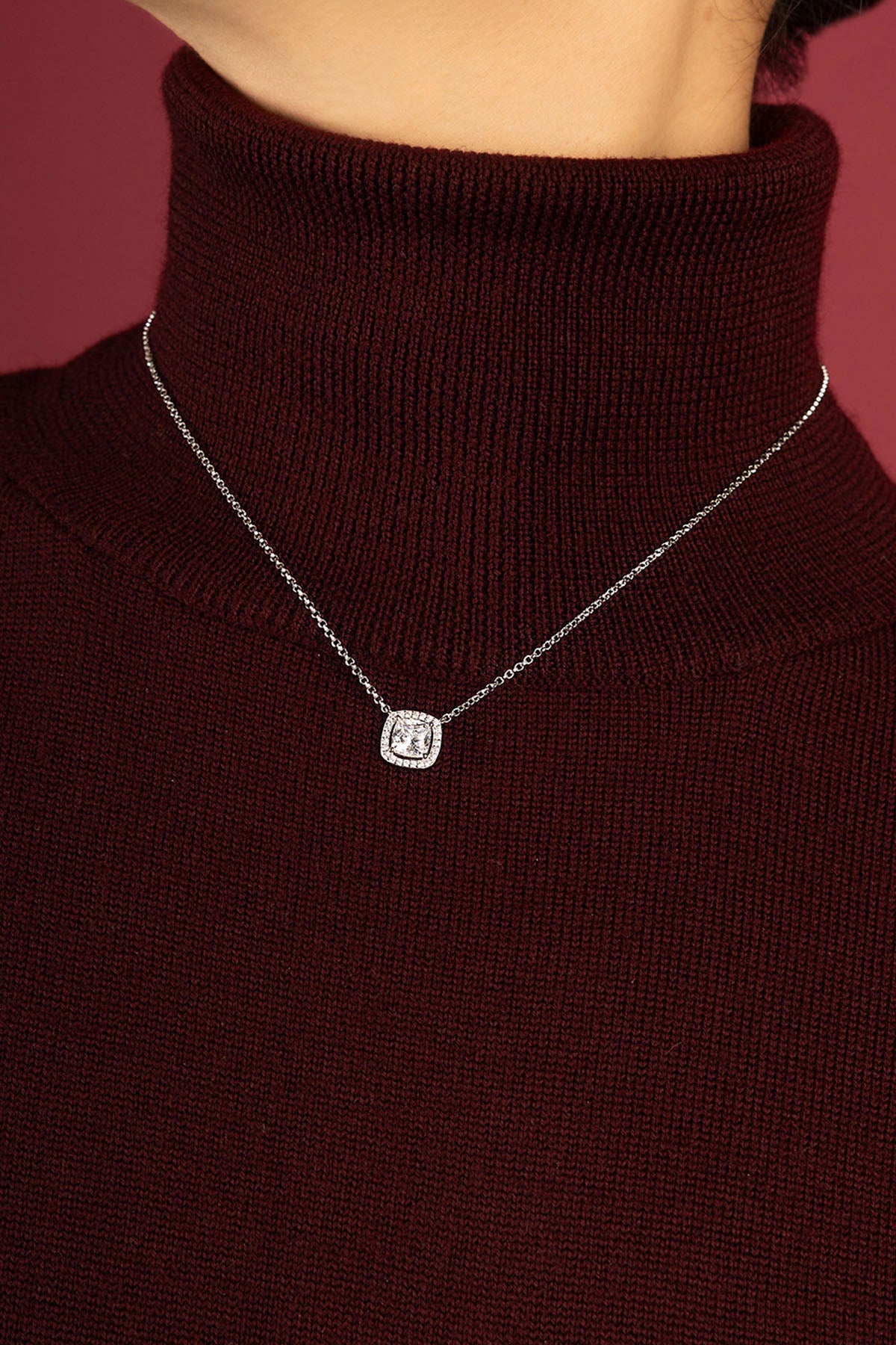 Femme portant le collier APM, éclat carré délicat sur col bordeaux.