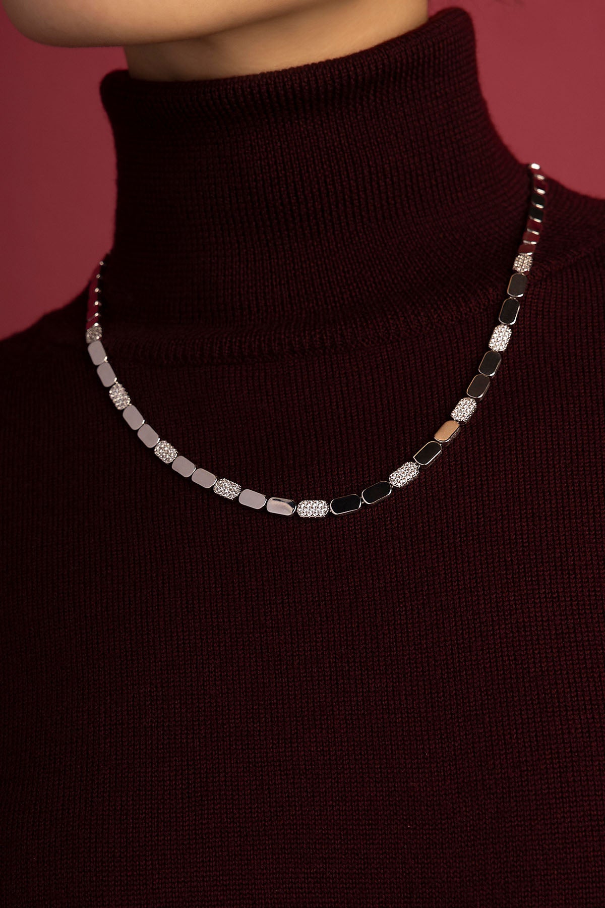 Femme portant le Collier APM, éclat scintillant sur col roulé bordeaux.