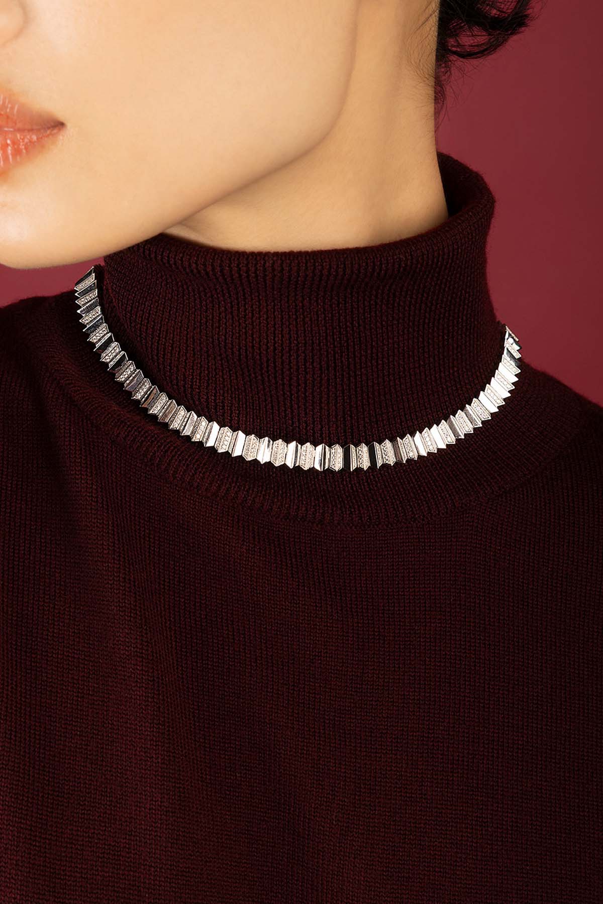 Femme portant le Collier APM, éclat graphique sur un hiver bordeaux.