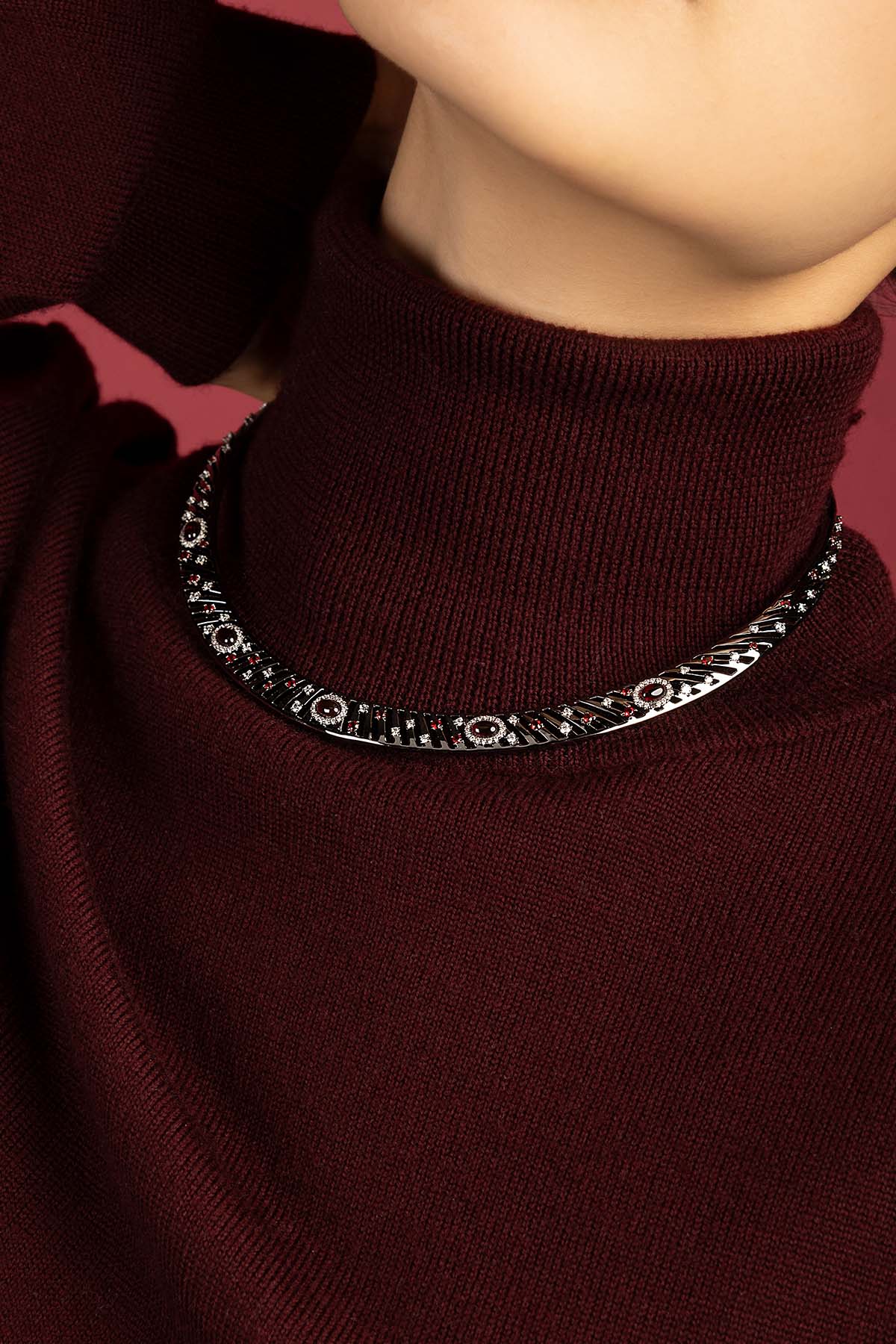 Femme portant le Collier Morse APM, éclat sophistiqué sur bordeaux profond.