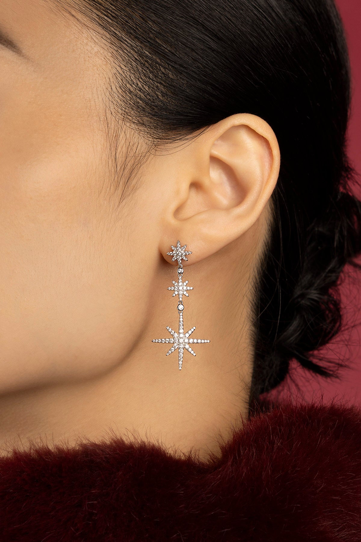 Femme portant les boucles d'oreilles APM Météorites, une cascade d'étoiles scintillantes.