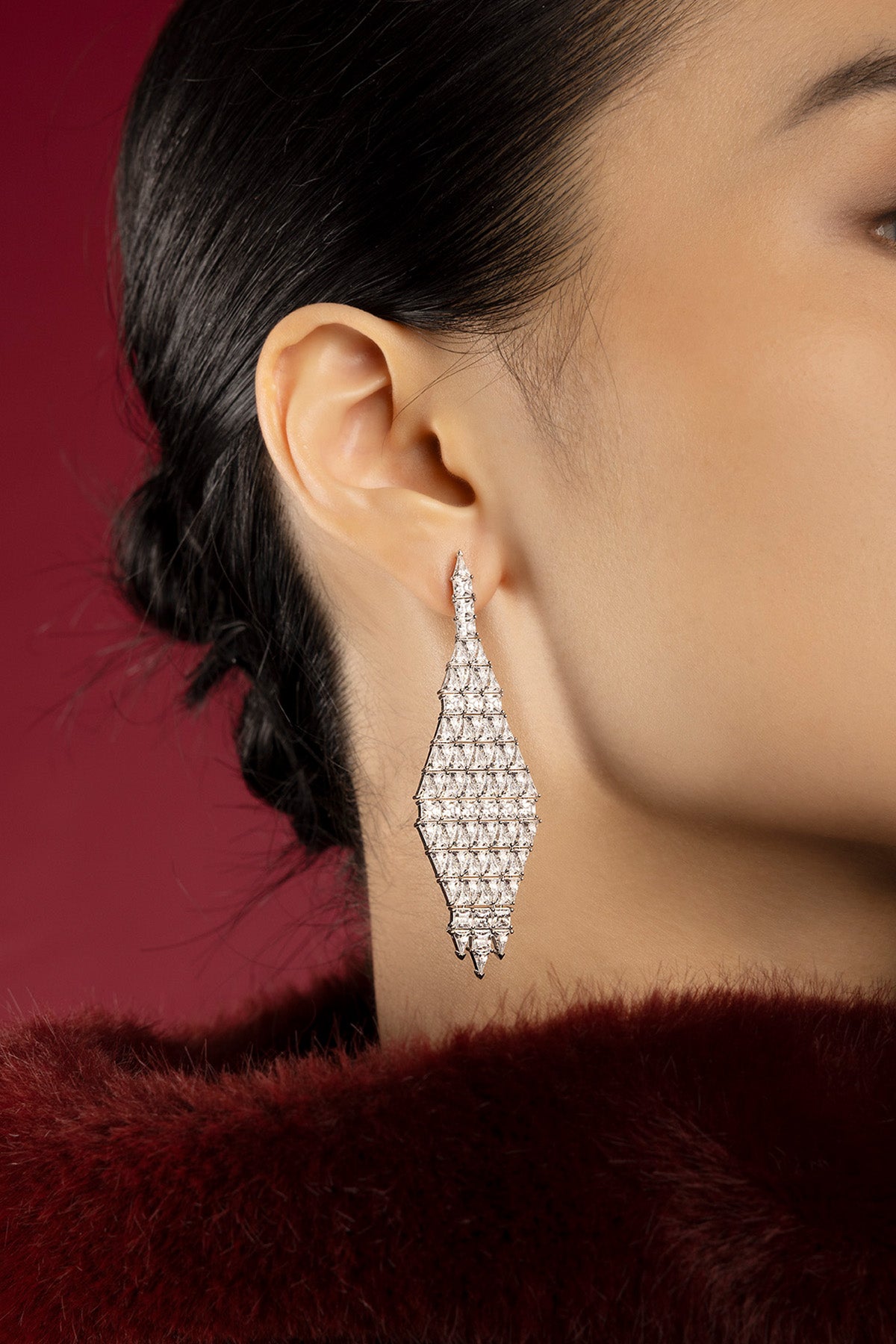 Femme portant les boucles d'oreilles APM, éclat géométrique d'une élégance nocturne.