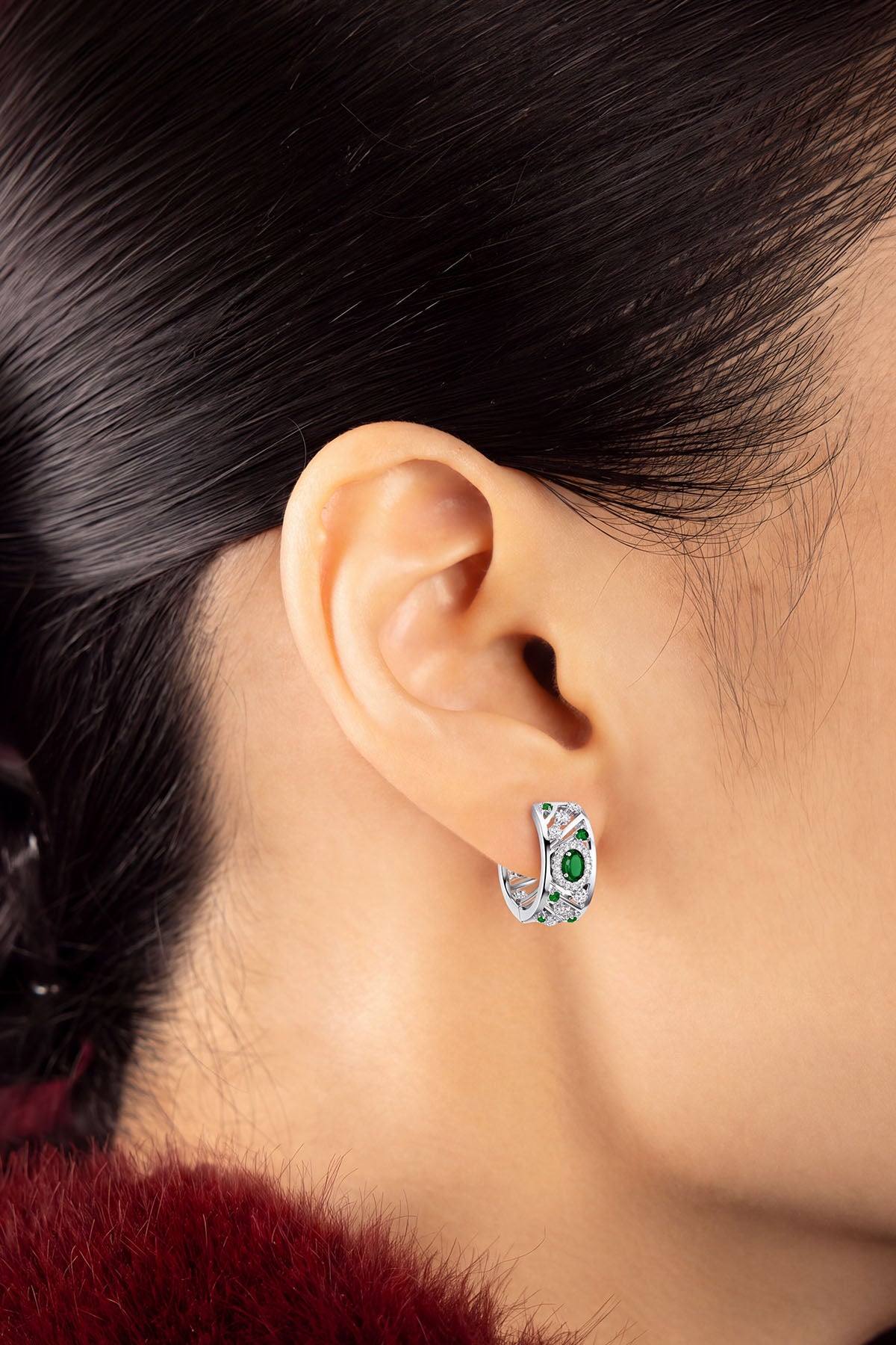 Femme portant les Créoles APM Monaco, éclat vert émeraude et finition rhodium tout en élégance.