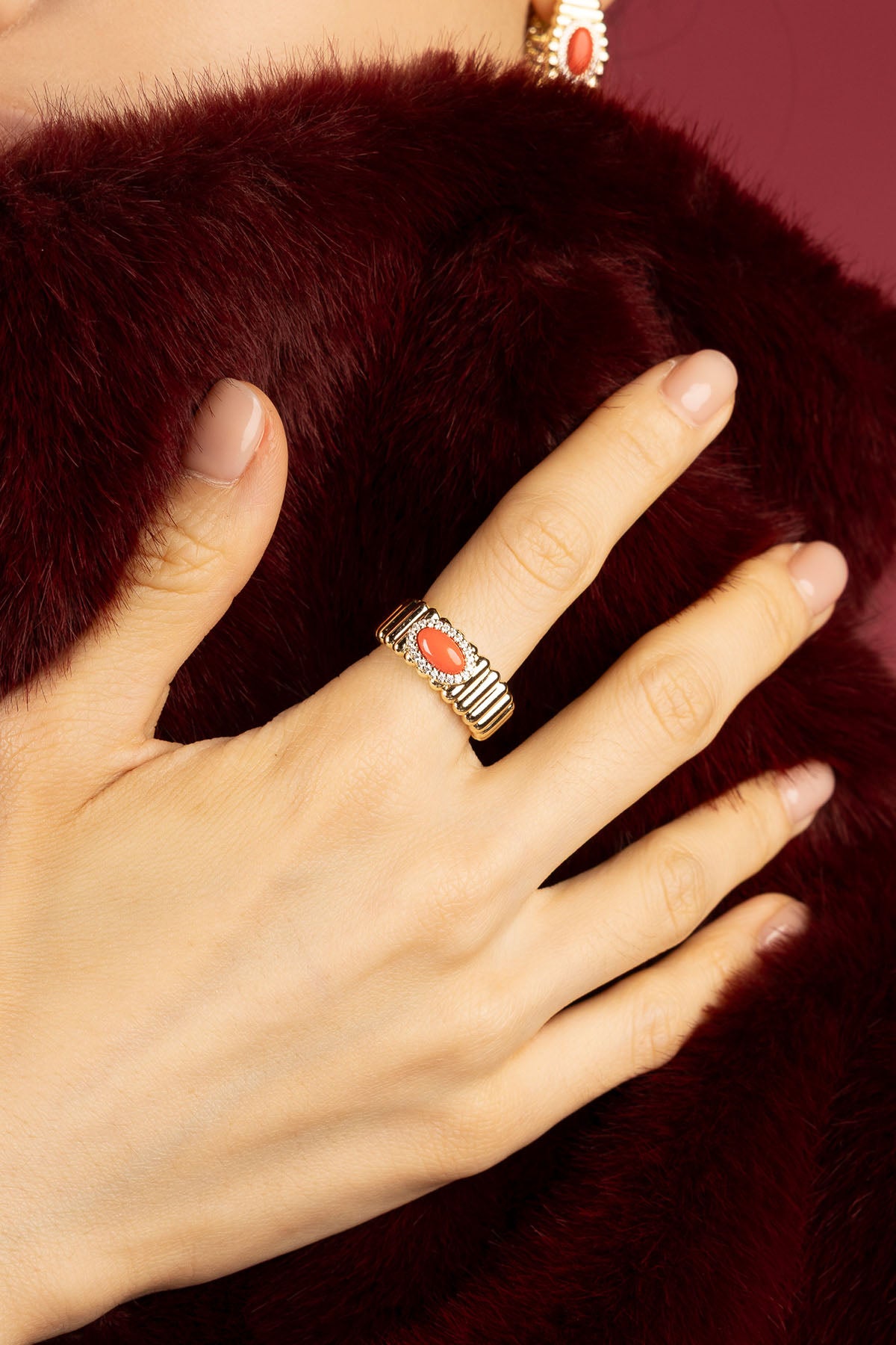 Femme portant la Bague APM Monaco, une touche corail pleine d'élégance chaleureuse.