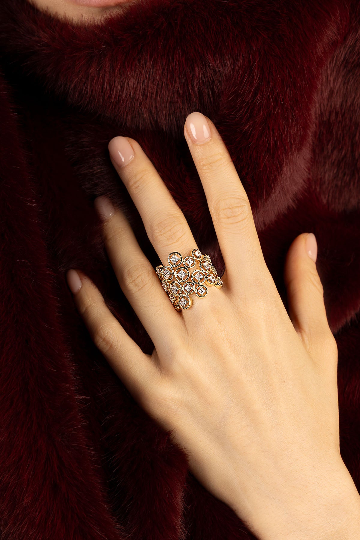 Femme portant la Bague APM Monaco, éclat doré et lumineux sur fourrure bordeaux.