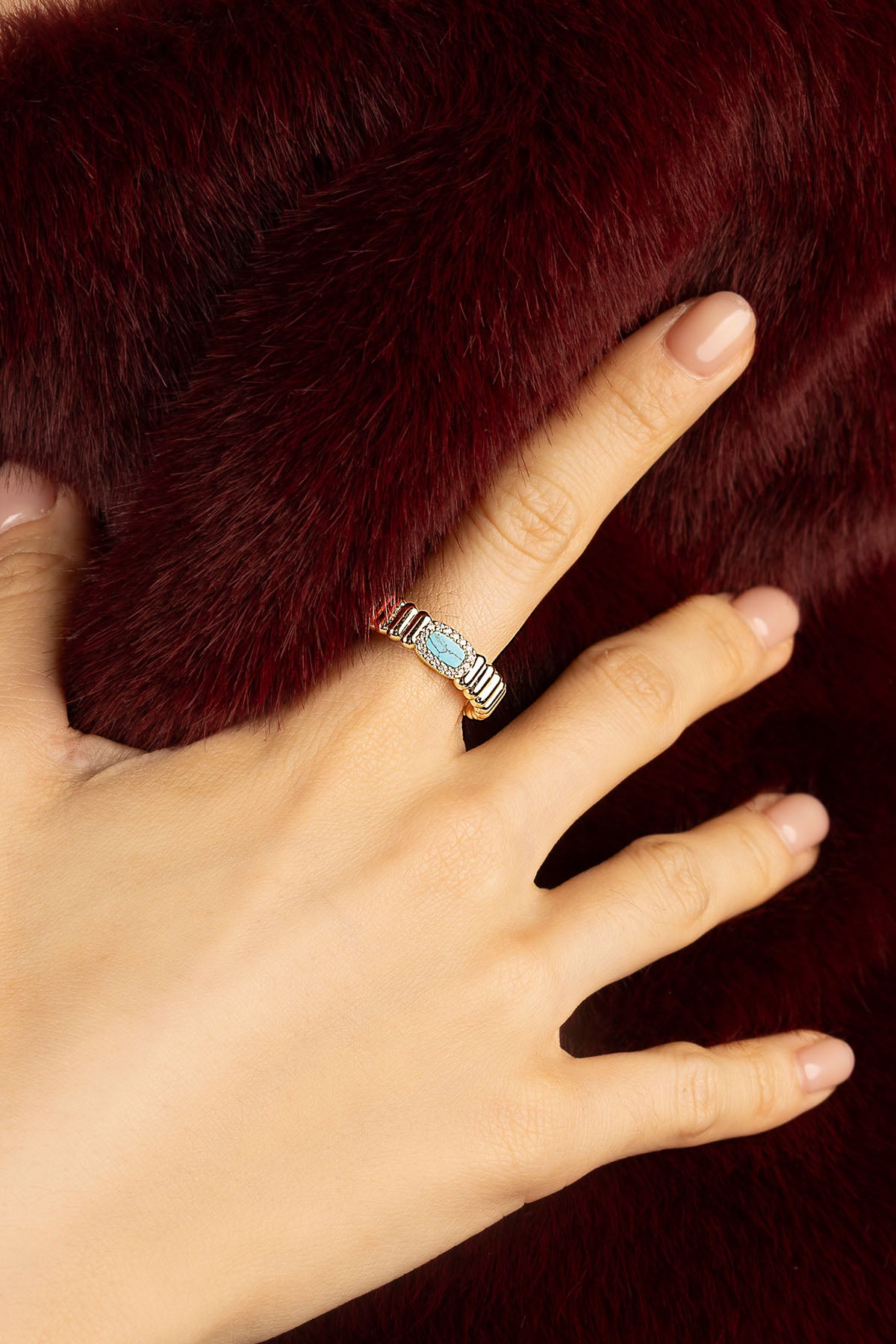 Femme portant la Bague APM, touche turquoise et éclat doré, élégance intemporelle.