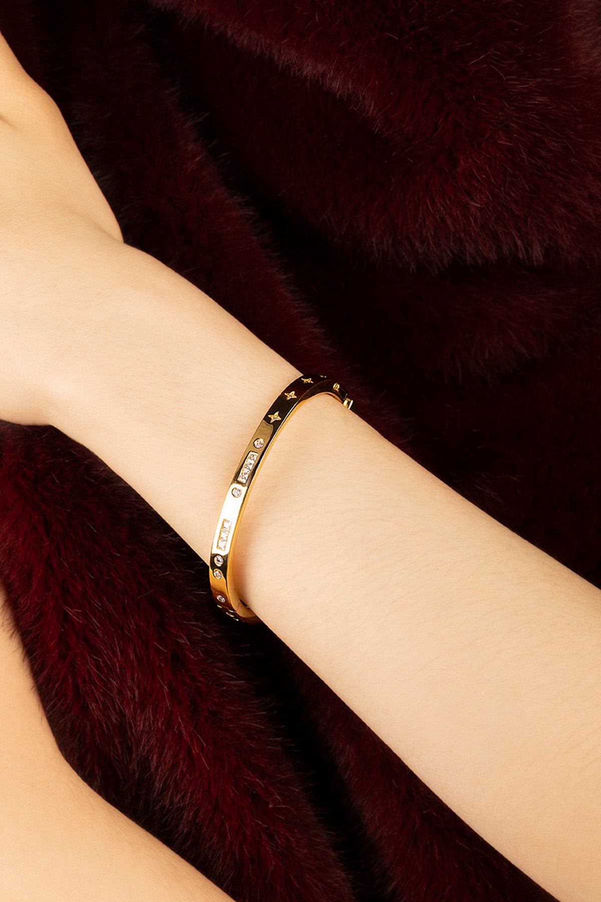 Femme portant le bracelet APM Monaco doré, une élégance stellaire posée sur la fourrure.