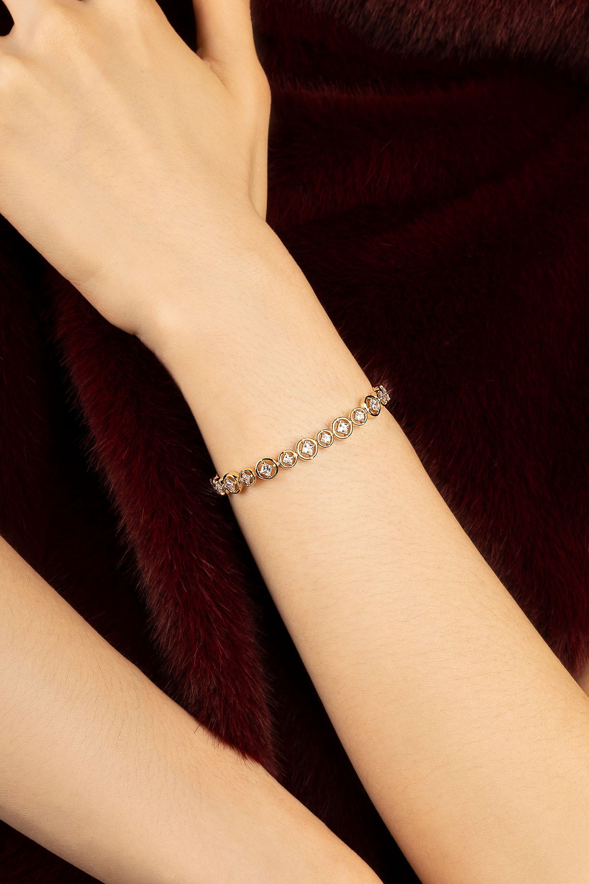 Femme portant le bracelet APM Monaco, une élégance dorée sur fourrure bordeaux.