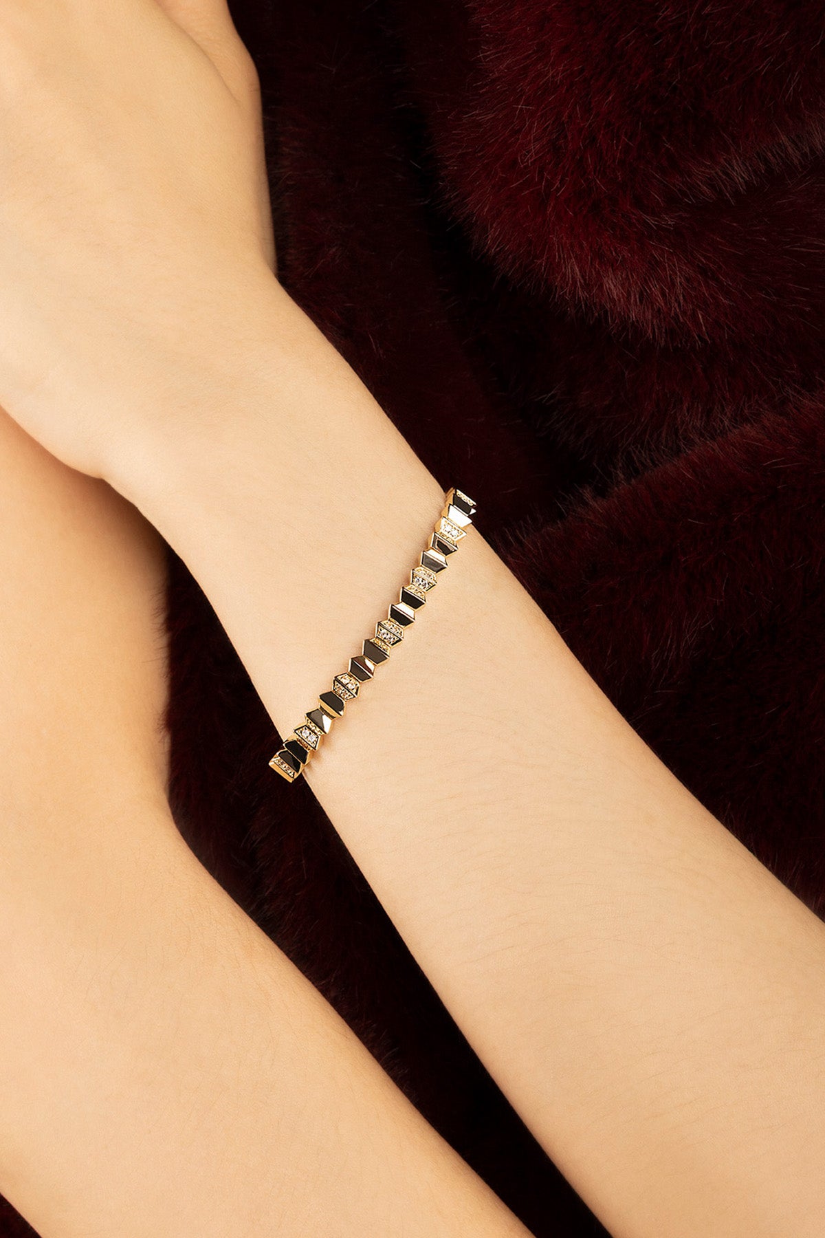 Femme portant le Bracelet APM Monaco, une allure graphique aux reflets dorés et noirs envoûtants.