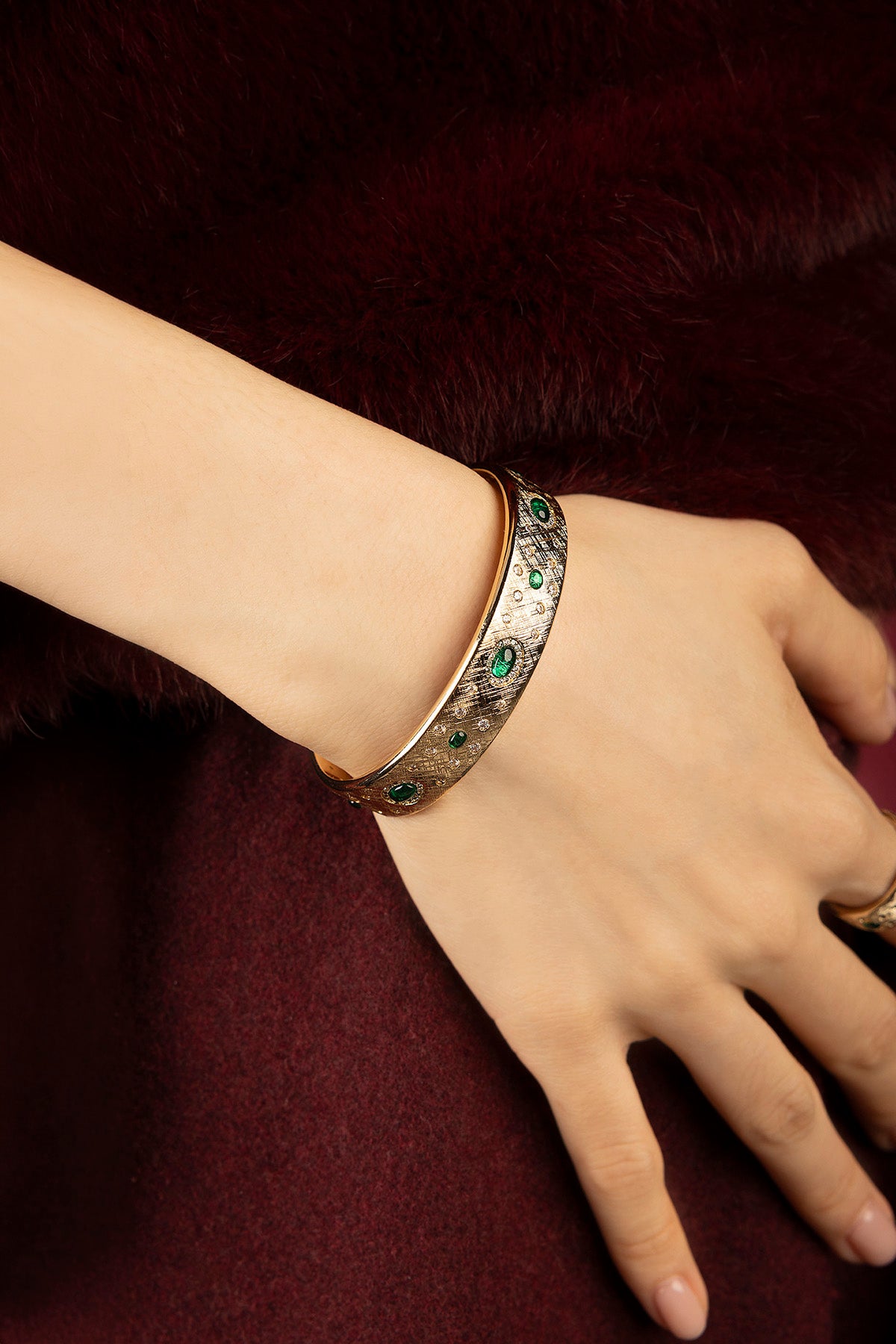 Femme portant le bracelet APM, éclats émeraude et allure vintage précieuse.