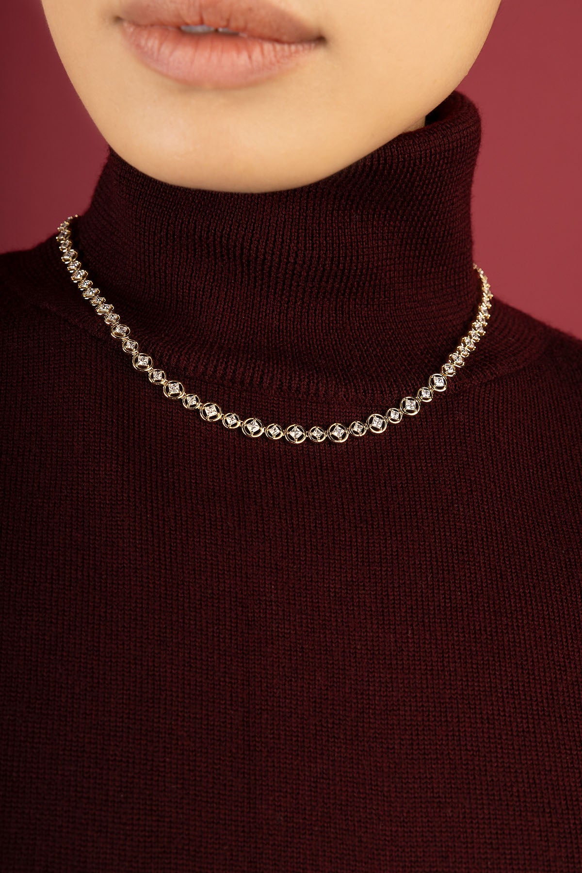 Femme portant le collier APM, éclat scintillant sur un col roulé bordeaux.