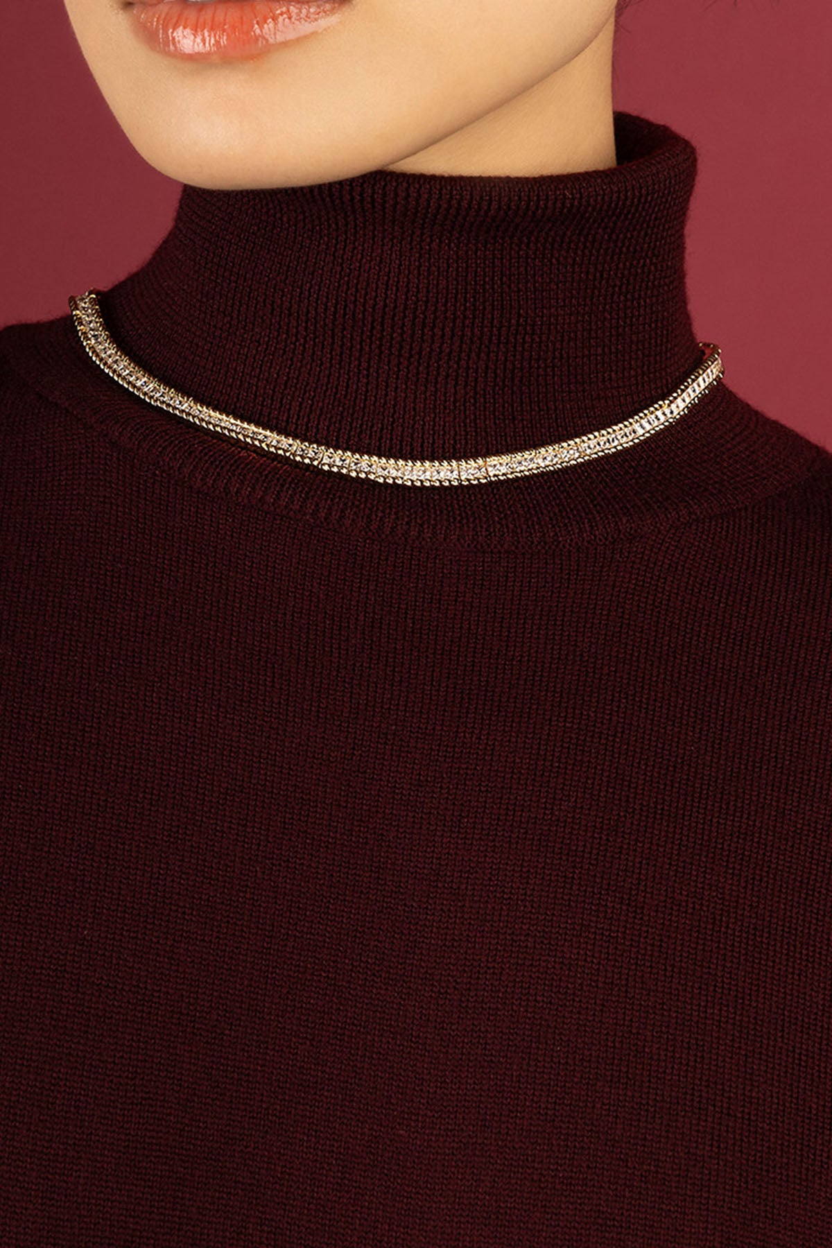 Femme portant le collier APM Monaco, éclat scintillant sur un col bordeaux.