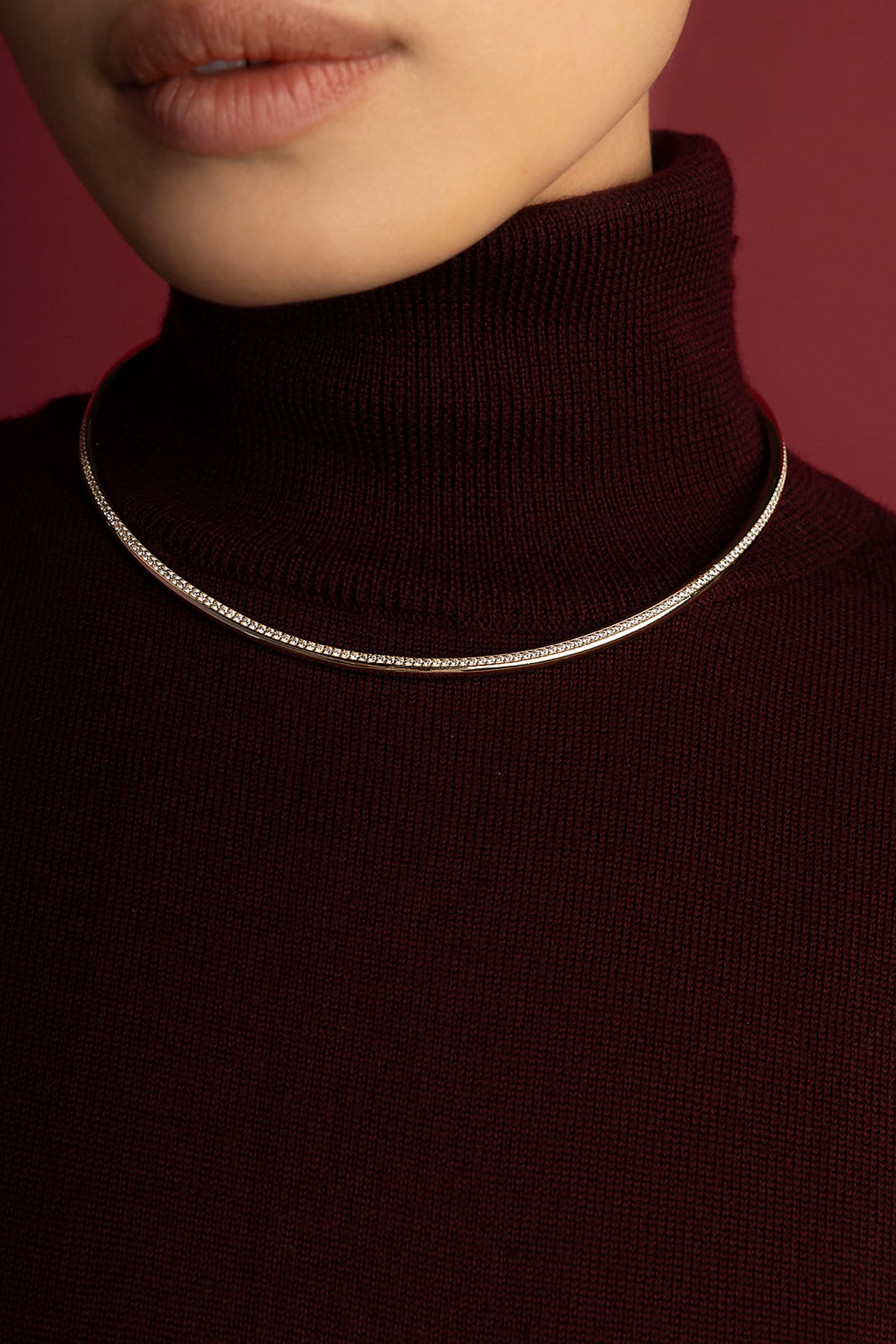 Femme portant un collier APM, éclat scintillant sur col roulé bordeaux.
