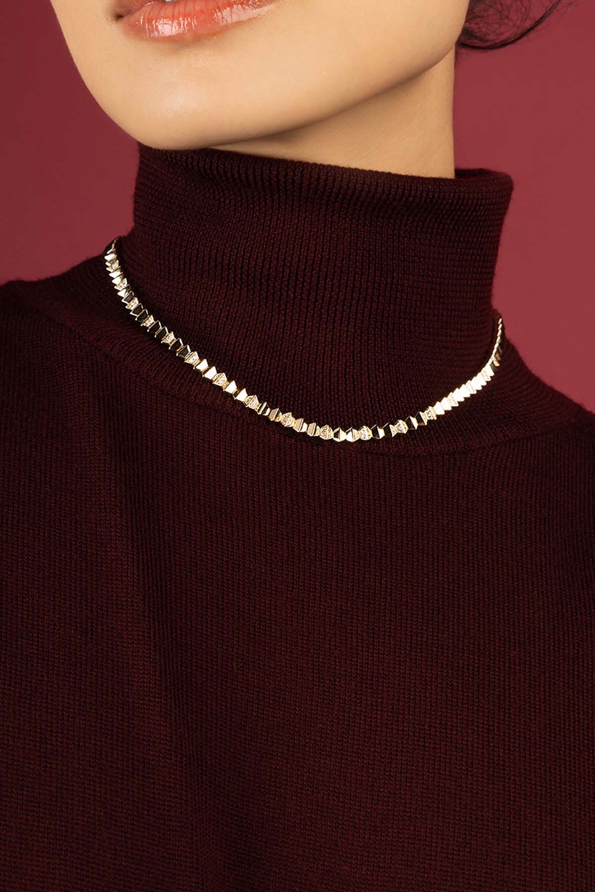 Femme portant le collier APM Monaco, éclat sculptural sur col bordeaux, allure moderne et raffinée.