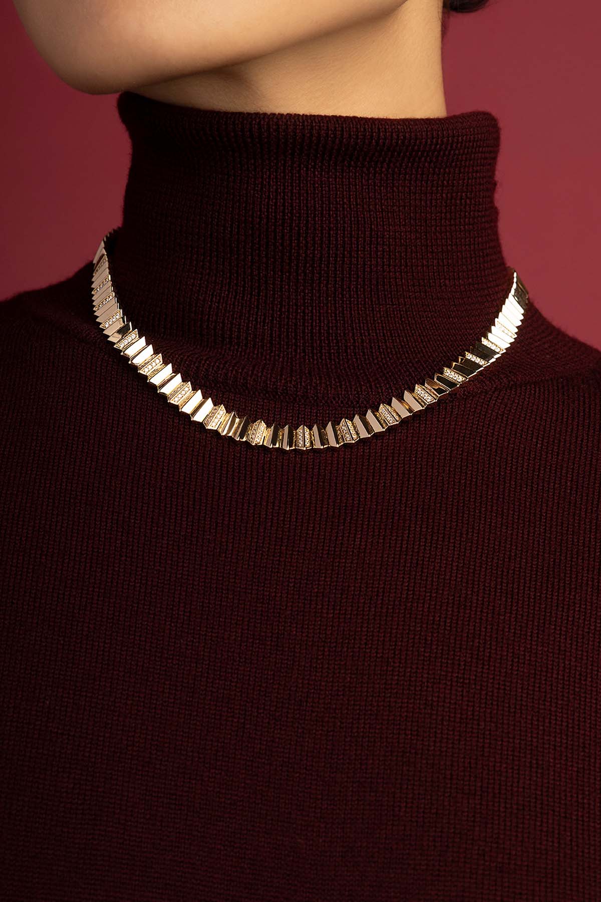 Femme portant le collier APM Monaco, éclat graphique sur bordeaux feutré.