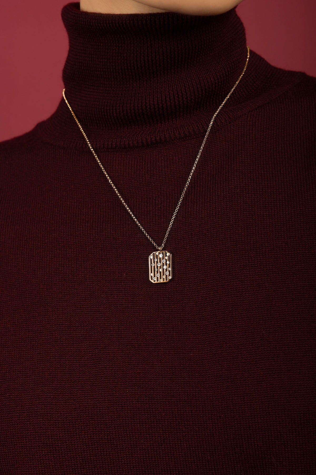 Femme portant le collier APM, une élégance dorée posée sur un col bordeaux.