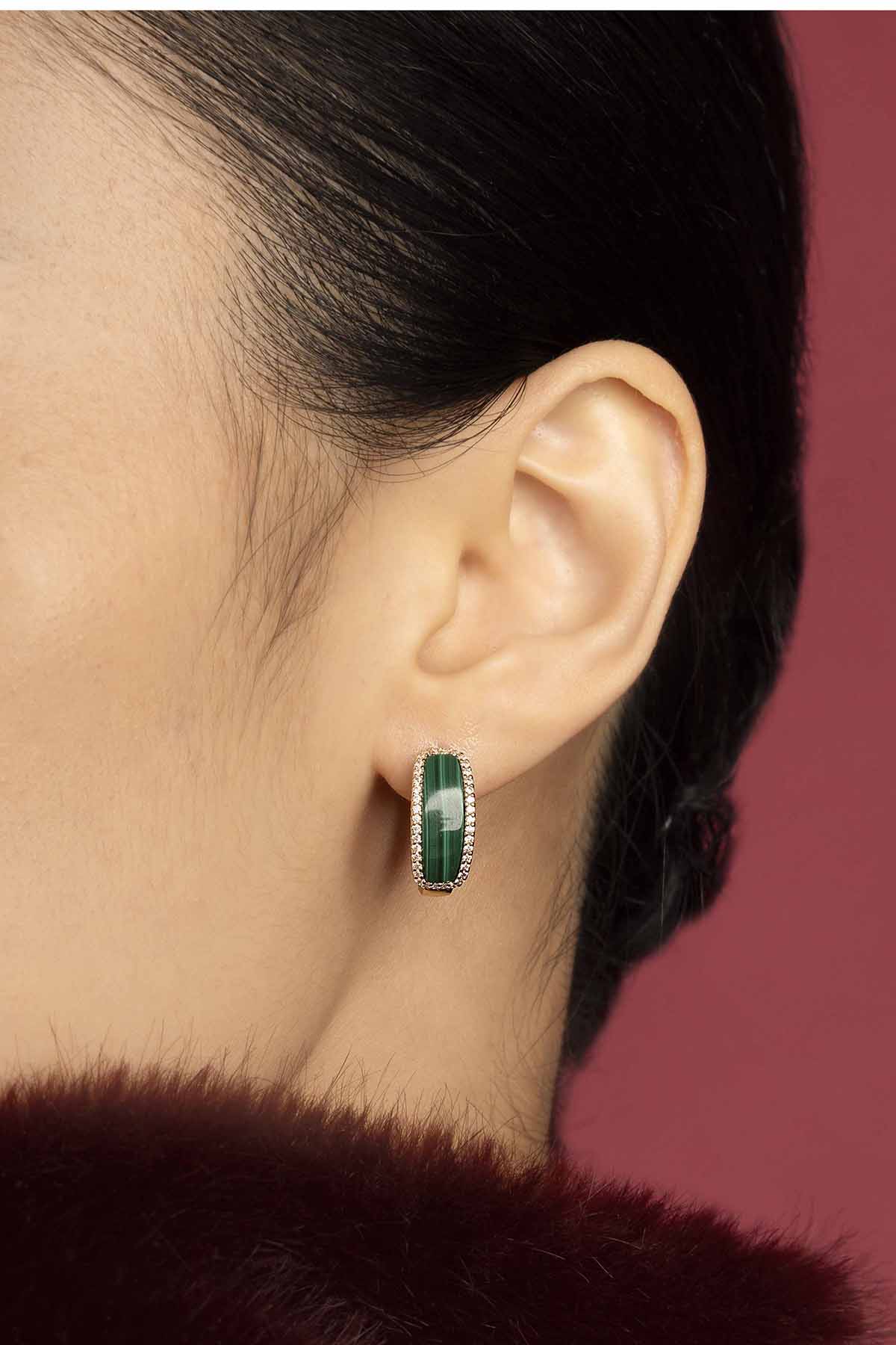 Femme portant les Boucles d'Oreilles APM, une touche de vert profond, élégance intemporelle.
