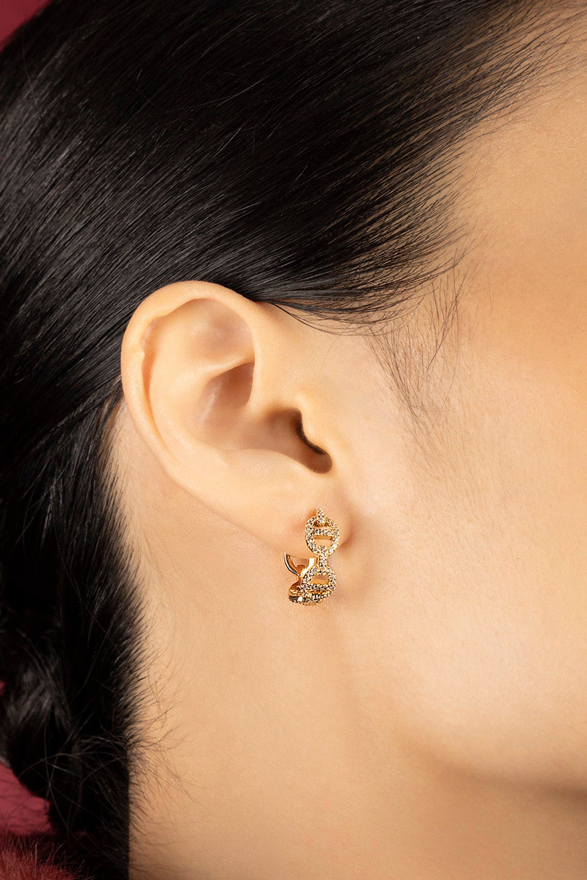 Femme portant les Boucles d'Oreilles APM, éclat doré et allure moderne et raffinée.