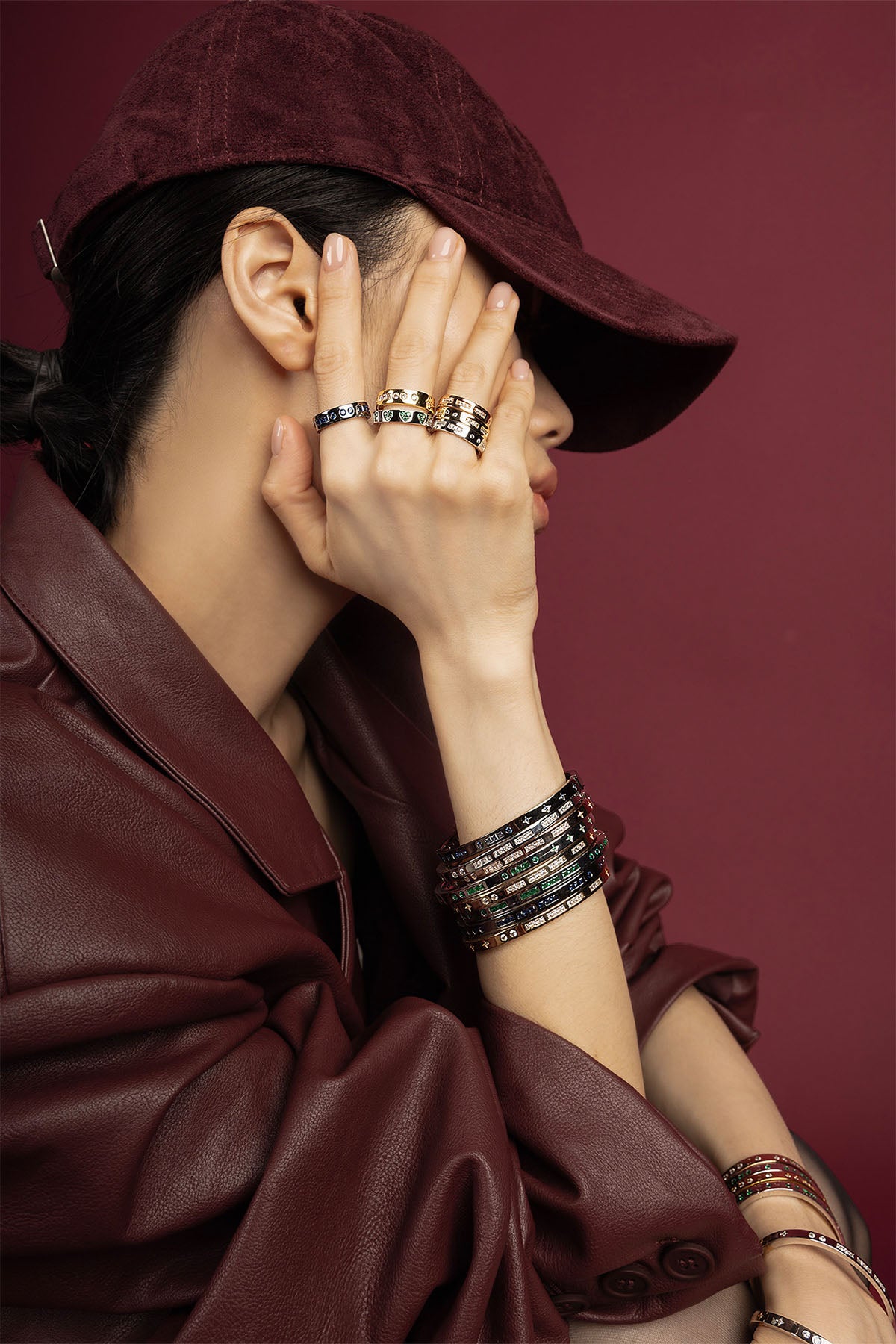 Woman wearing APM bracelets and rings, une allure audacieuse en bordeaux profond.