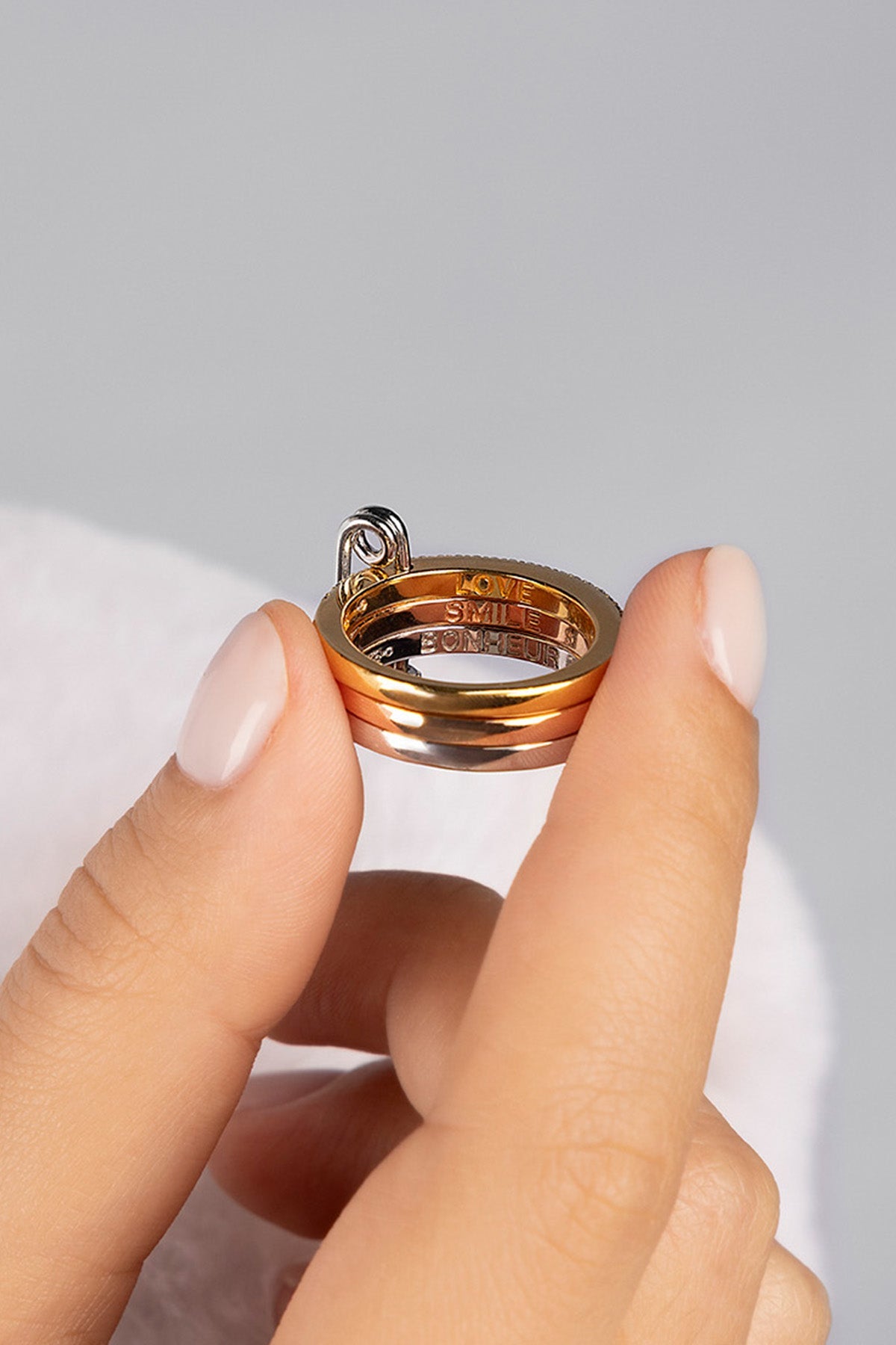 Rings APM Monaco fashion jewelry: a white, triple-hoop safety-pin ring with pavé cubic zirconia, paired with two additional cubic zirconia rings.