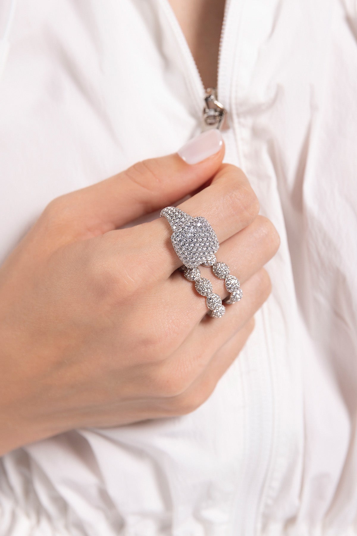 APM MONACO silver ring with white stones on a hand wearing a white shirt