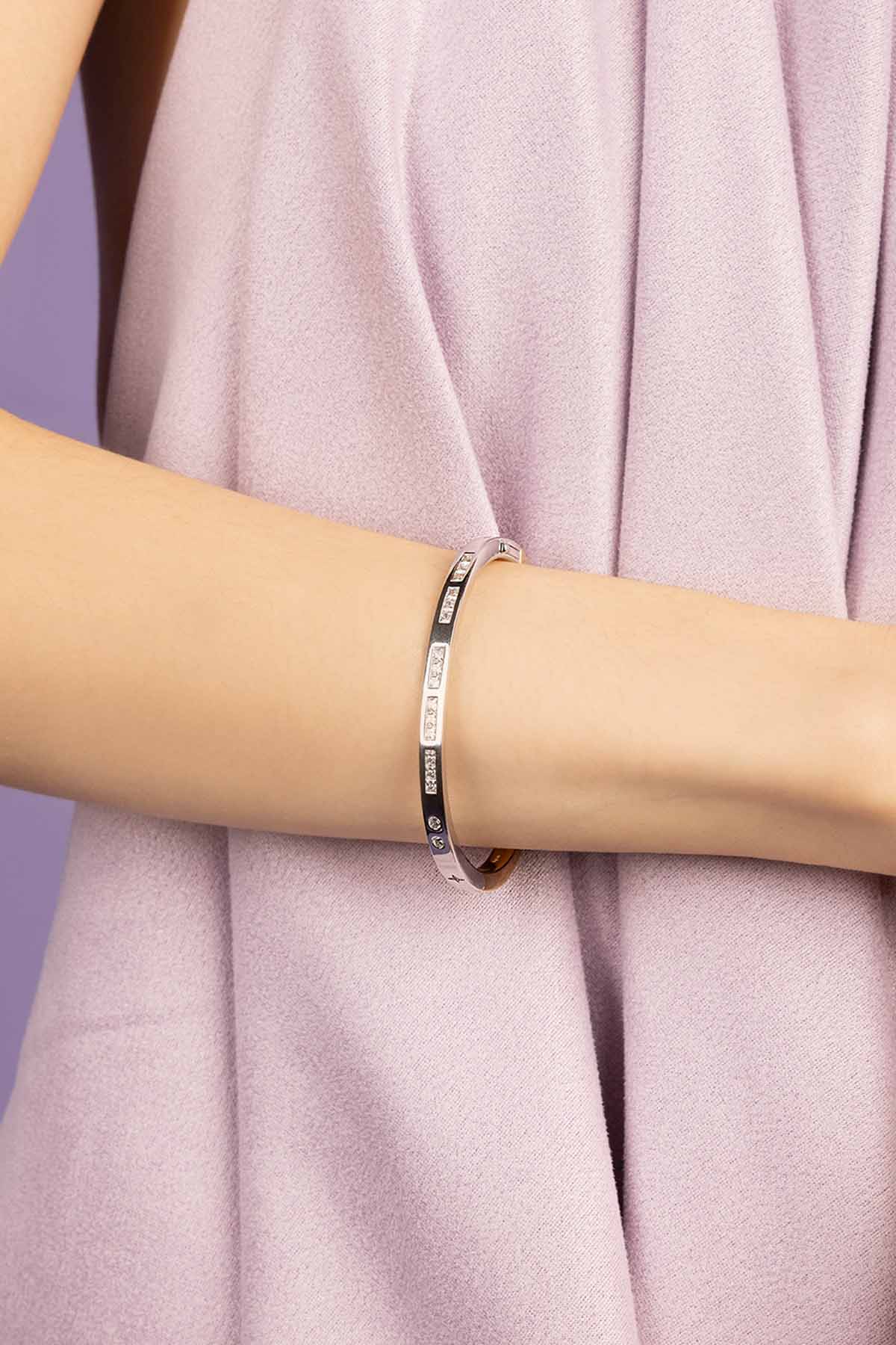 Rose gold bracelet on a person's wrist against a white background