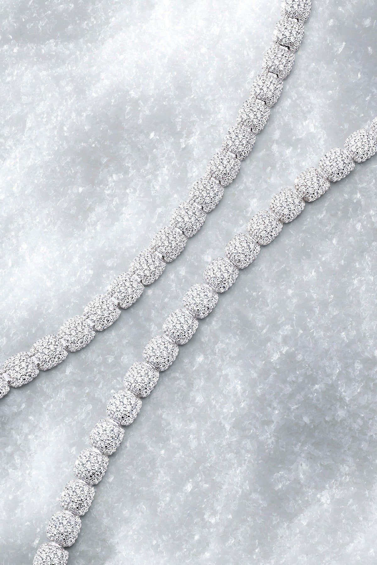 Two pave bracelets on a textured iced surface