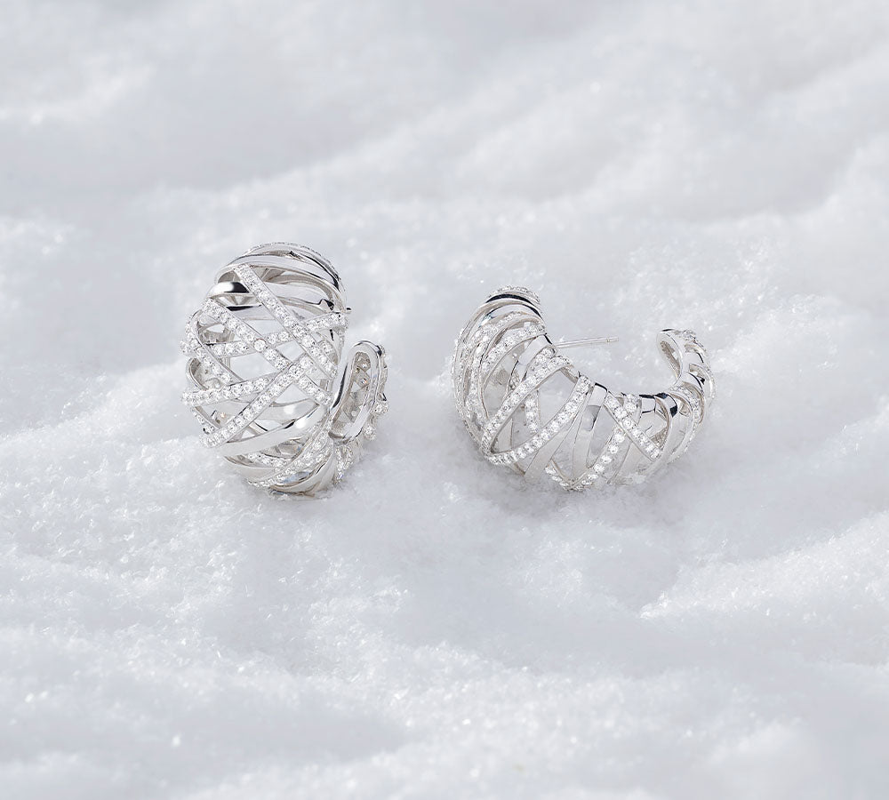A pair of APM MONACO enlace earrings in silver on snowy surface