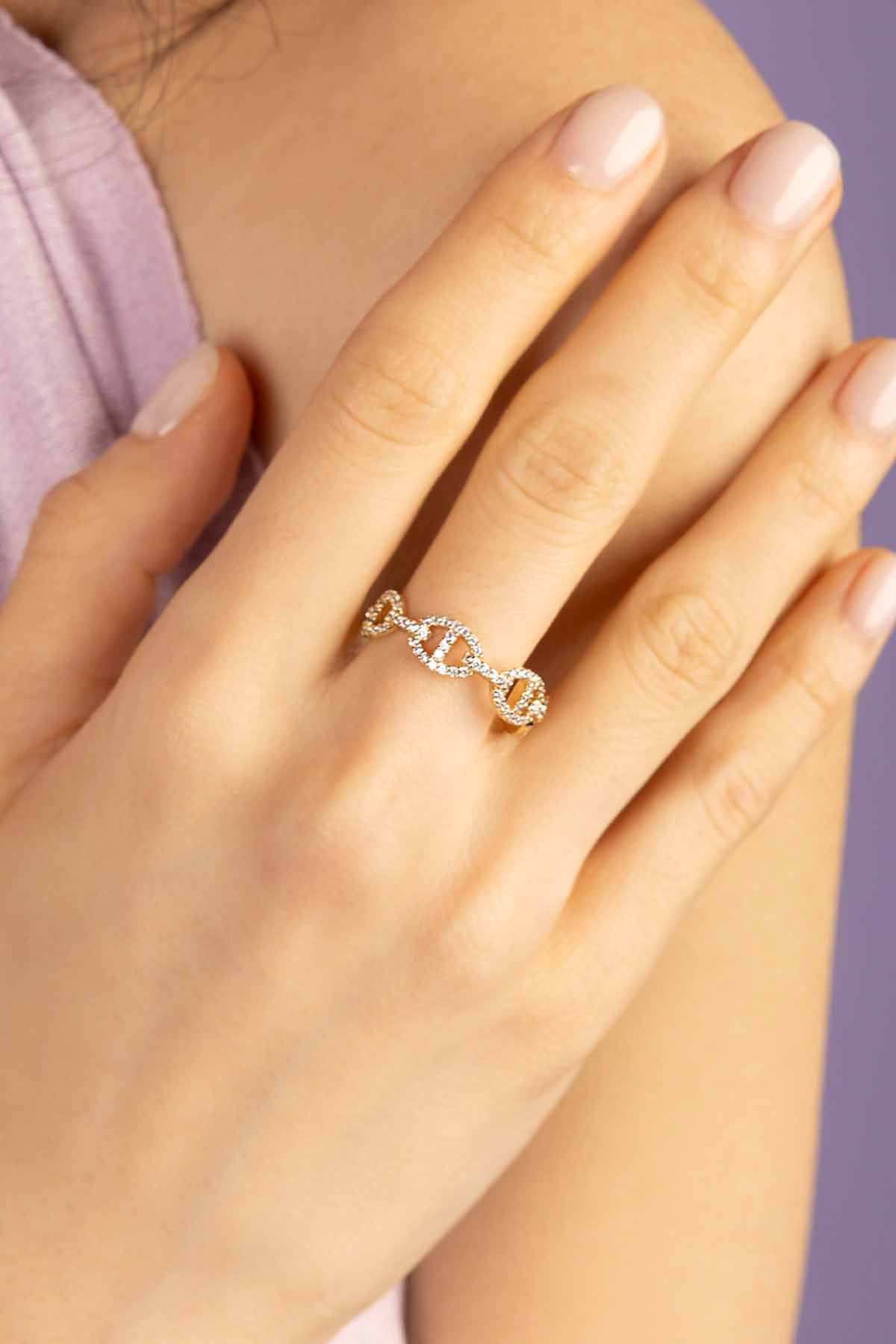 Hand wearing a diamond ring with a dark coat background