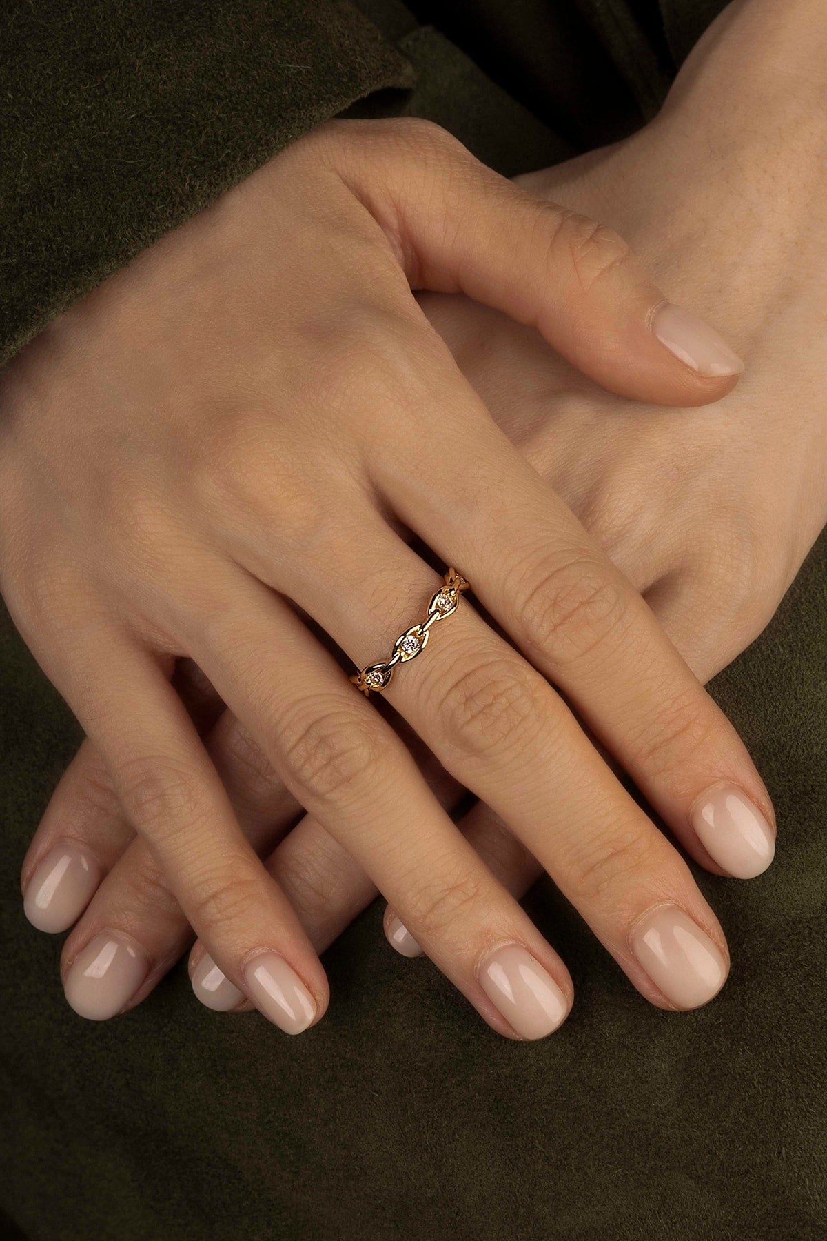 Close-up of a hand wearing a gold ring with a dark background