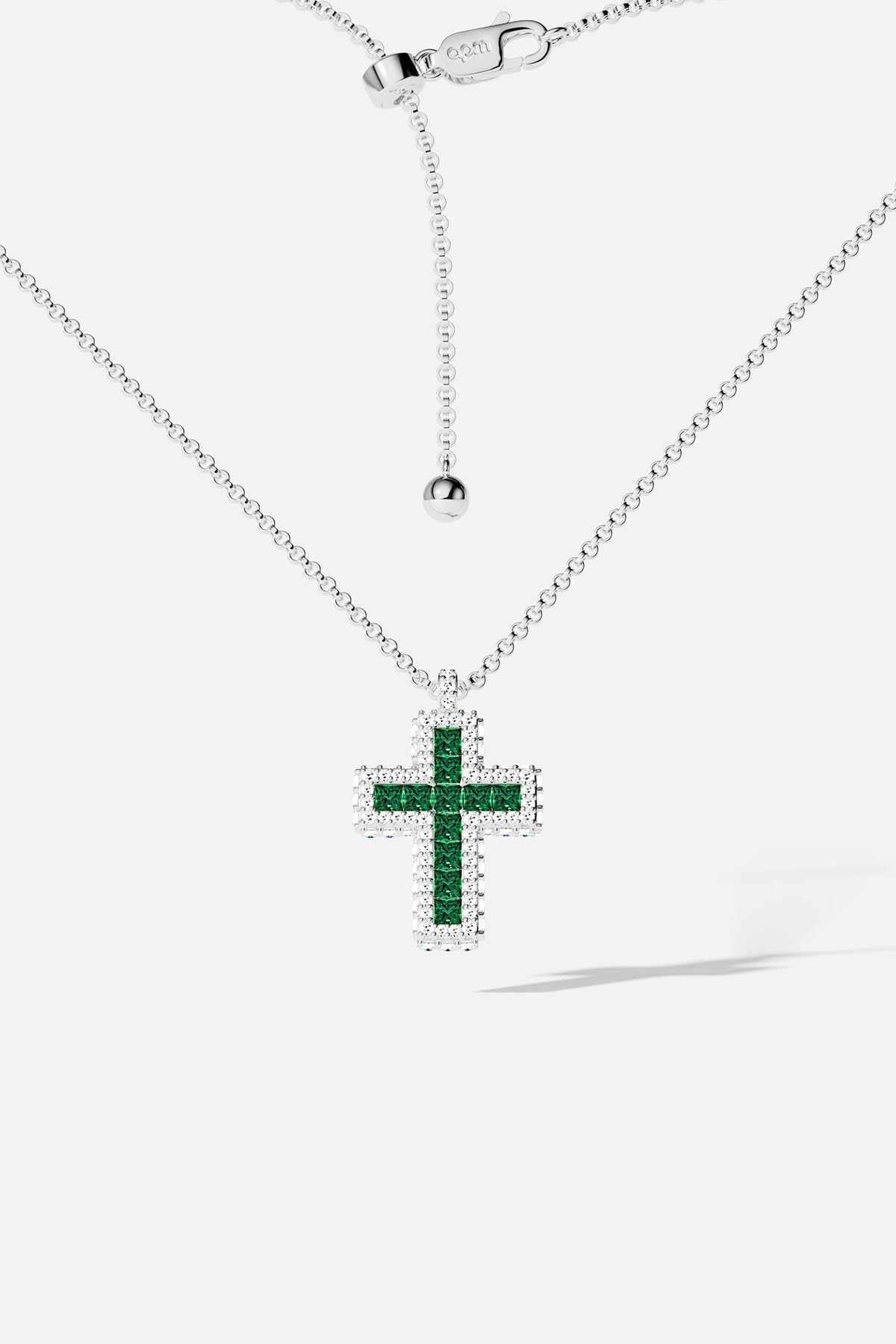 Collier APM croix, éclat vert émeraude et finition rhodium, une élégance intemporelle.