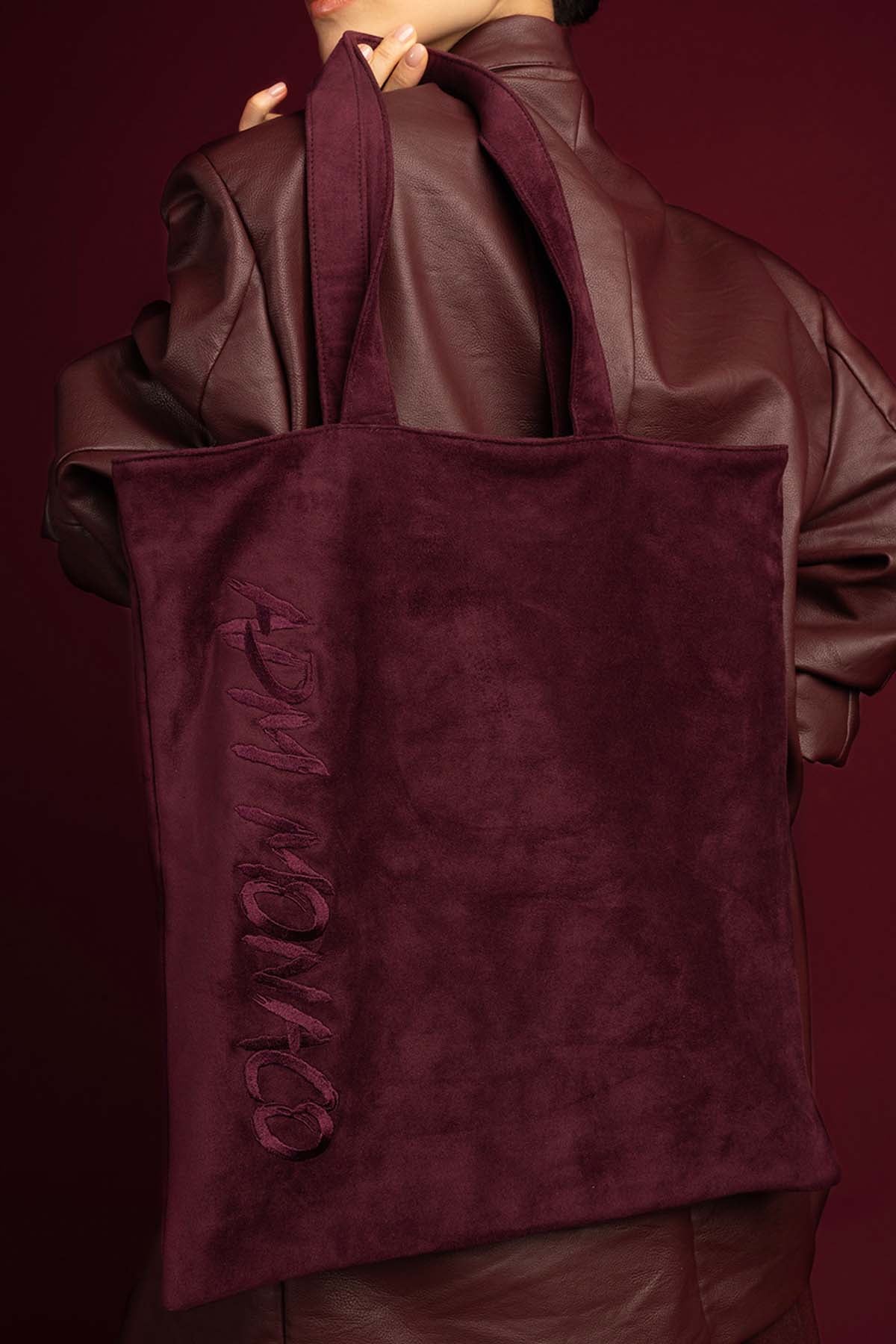 Femme portant le tote bag APM Monaco, allure bordeaux profonde et élégance décontractée.