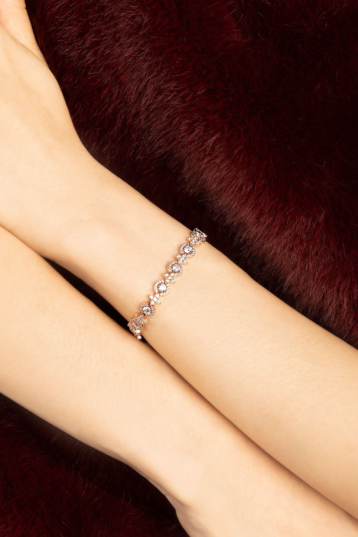 Femme portant un bracelet APM Monaco, éclat délicat sur fond velours bordeaux.