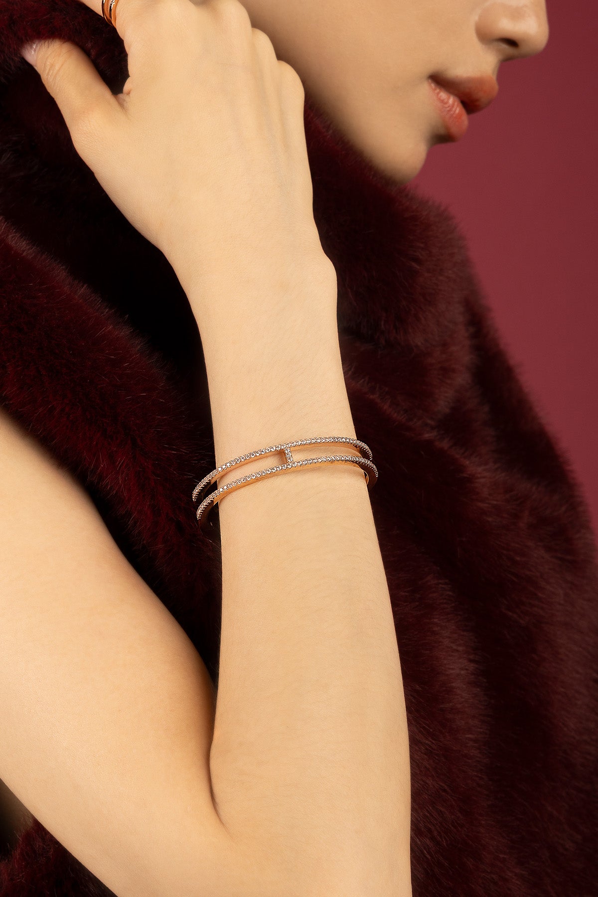 Femme portant le bracelet APM, éclat scintillant sur velours bordeaux, élégance intemporelle.