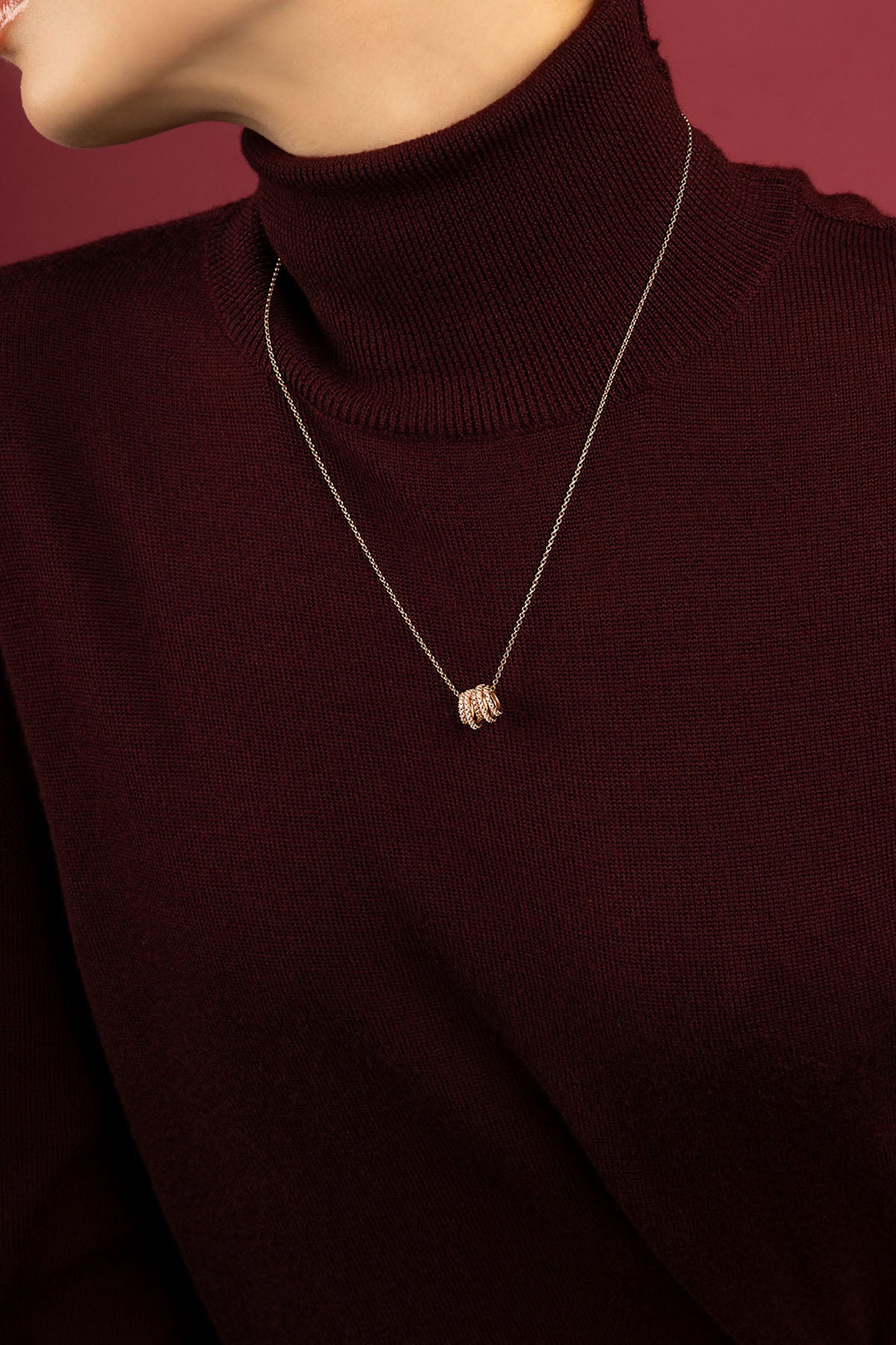 Femme portant le collier APM, une touche lumineuse sur un col roulé bordeaux.