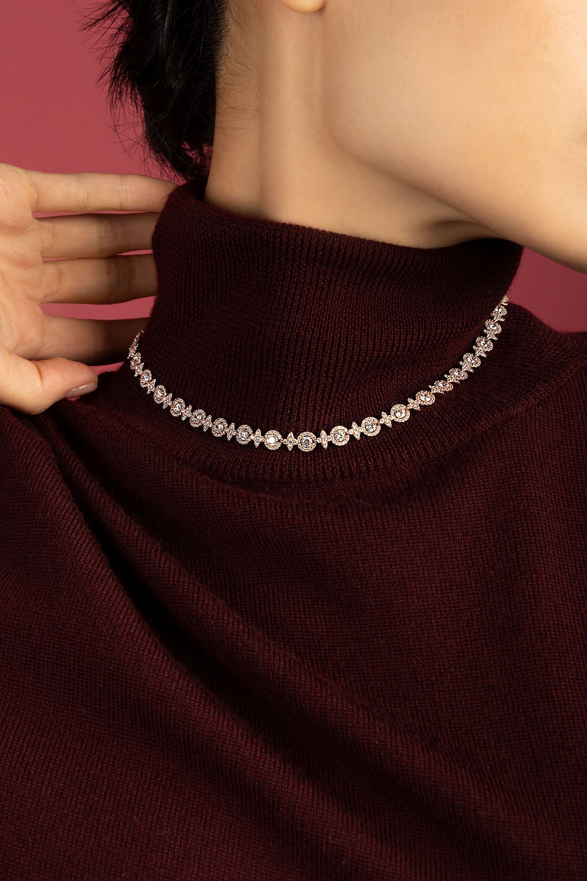 Femme portant le collier APM, éclat scintillant sur un col bordeaux hivernal.