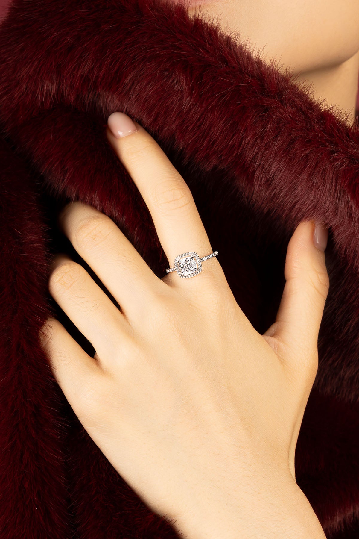 Femme portant une bague APM Monaco, éclat scintillant sur fourrure bordeaux.