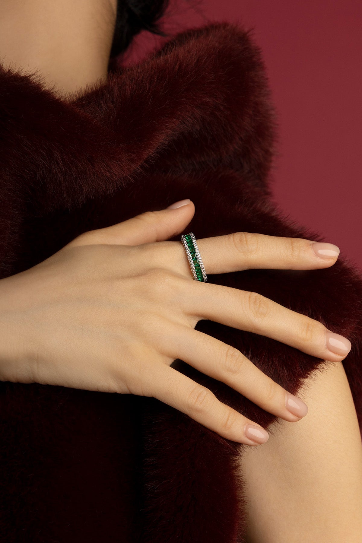 Femme portant la bague APM Monaco, éclat vert émeraude sur allure feutrée.